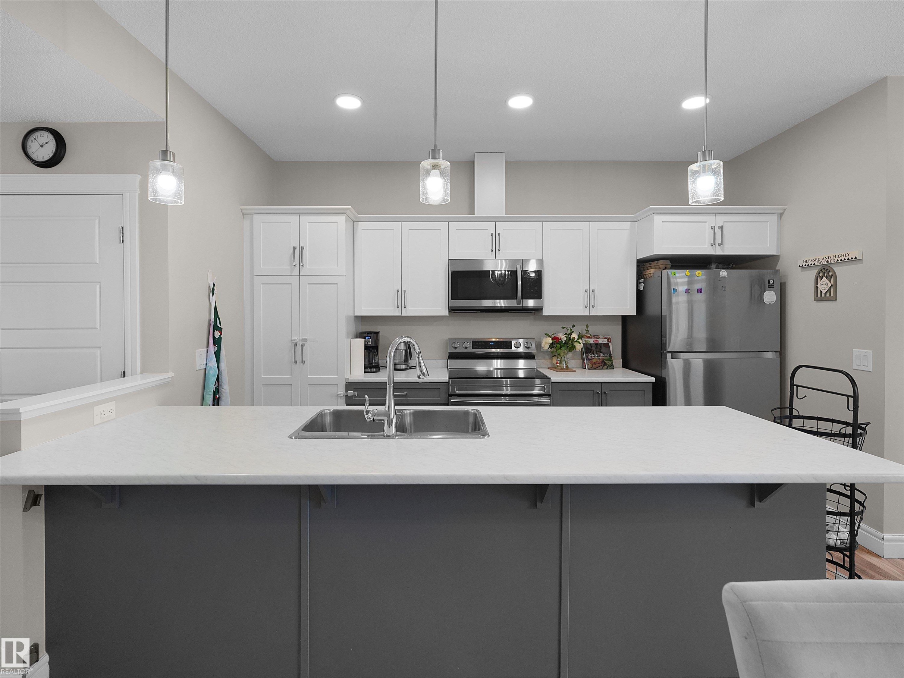 Expansive kitchen island with a light-toned countertop and integrated double basin sink - #30 4137 76 St Nw, Edmonton, AB