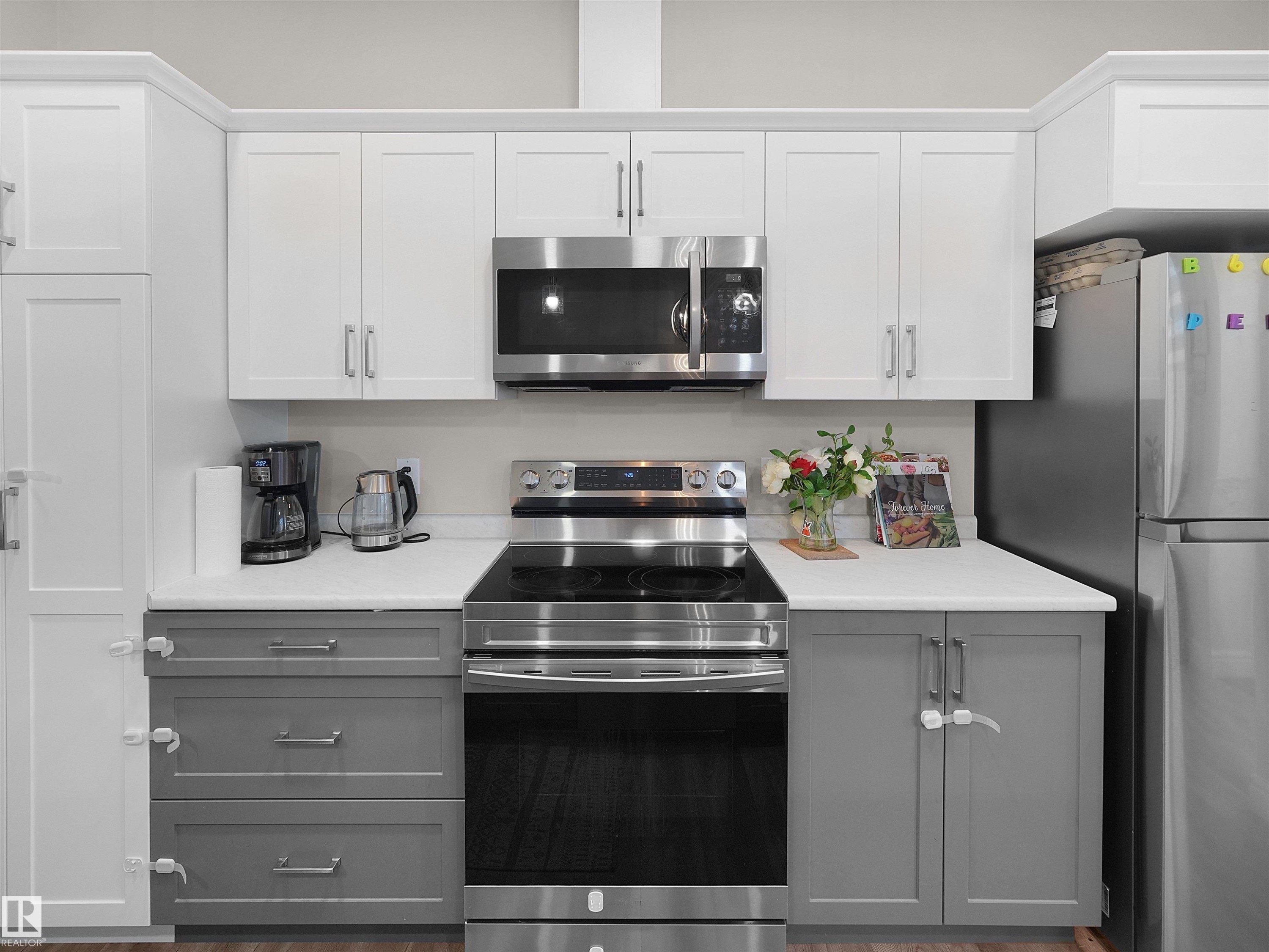 Contemporary kitchen featuring white upper cabinetry, gray lower cabinetry, stainless steel appliances, a built-in microwave, and a smooth-top range - #30 4137 76 St Nw, Edmonton, AB