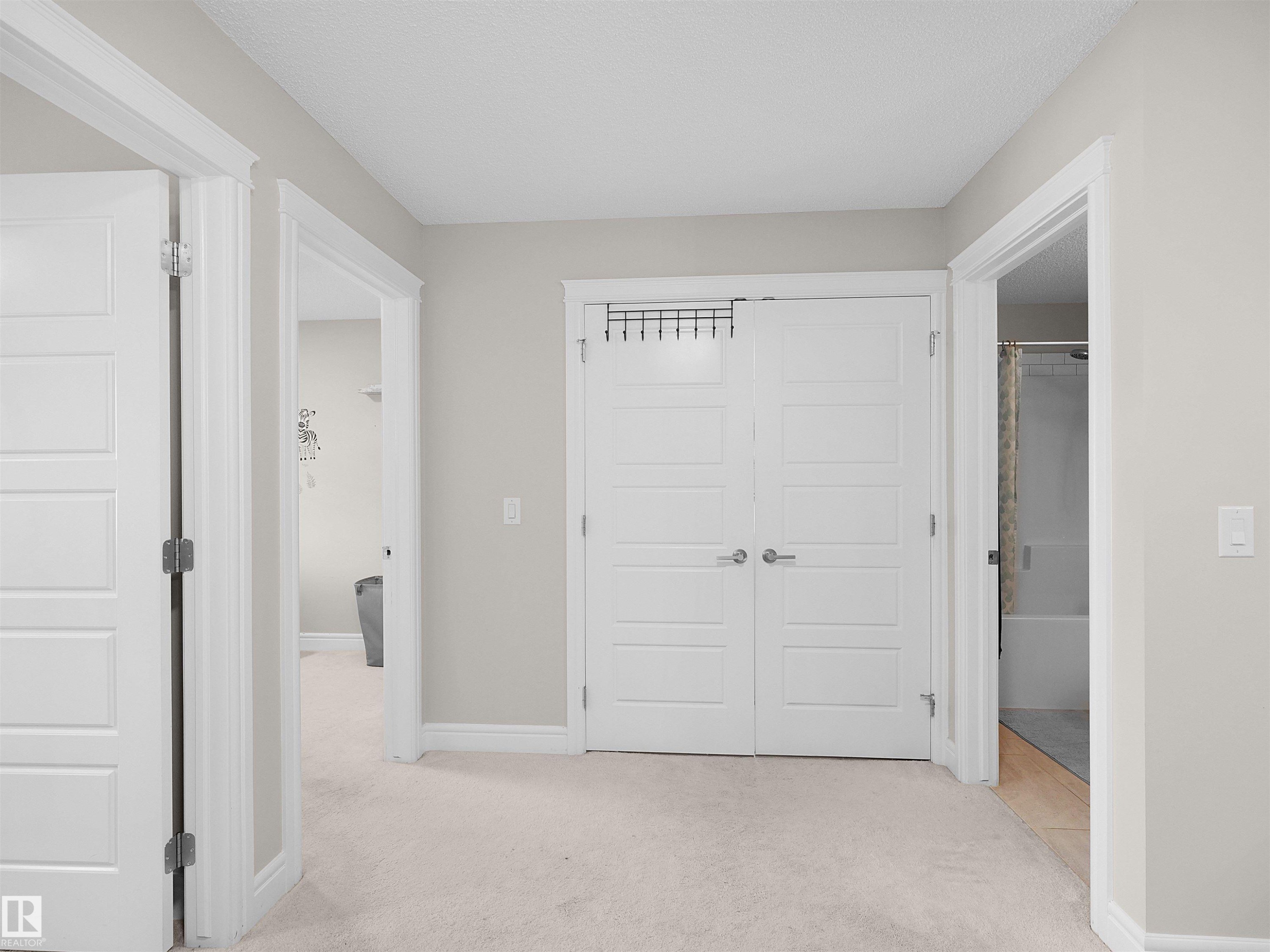 Hallway featuring light-colored carpet flooring, painted walls, and white trim - #30 4137 76 St Nw, Edmonton, AB