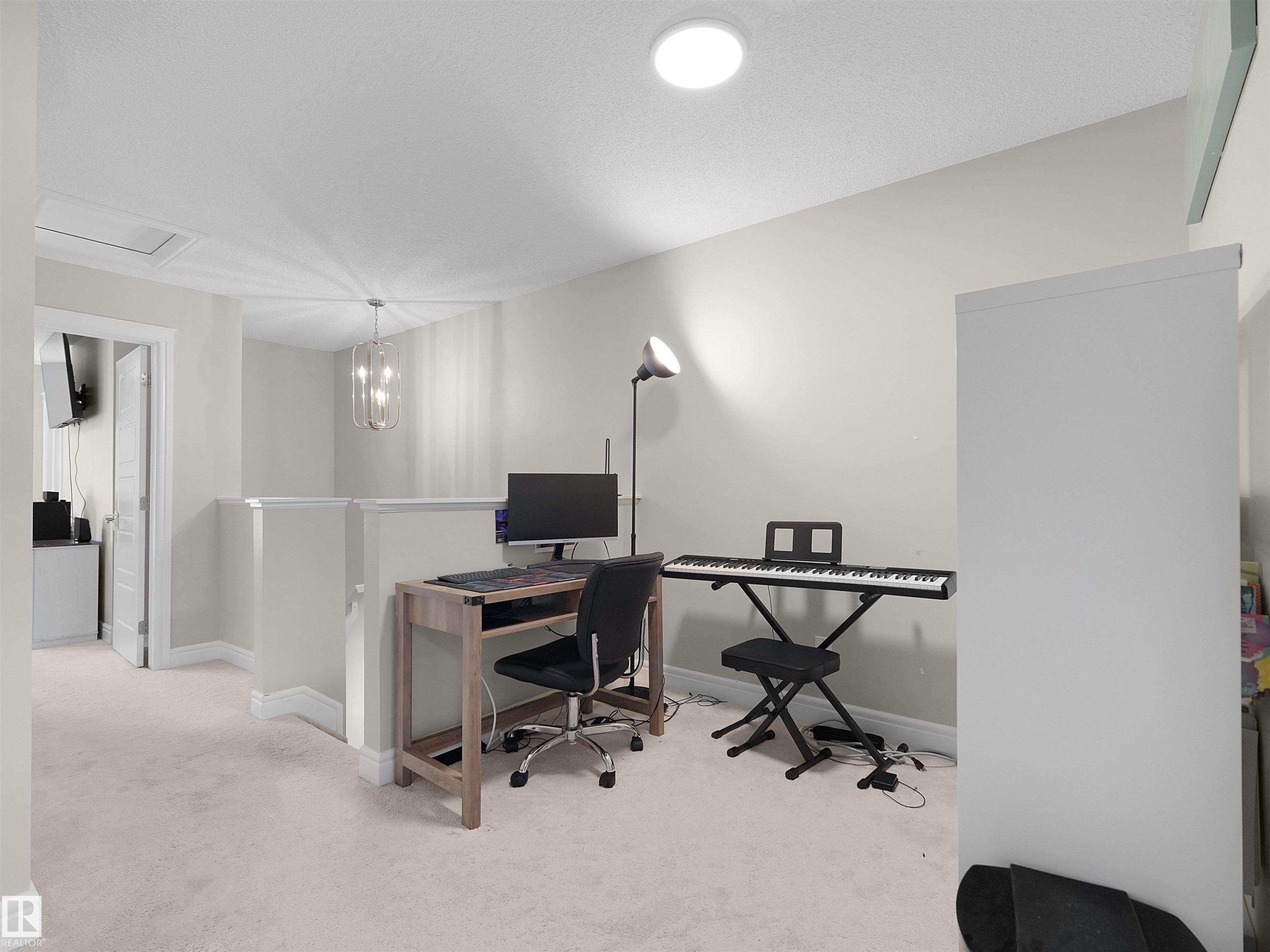 Carpeted loft area featuring a partial wall, overhead lighting, and a contemporary chandelier - #30 4137 76 St Nw, Edmonton, AB