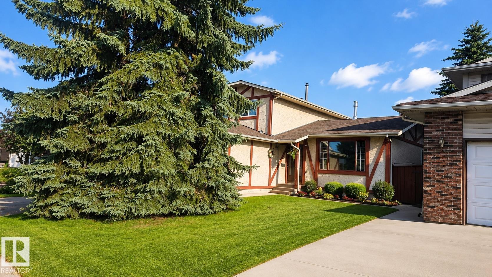 Exterior featuring stucco siding with timber accents, a brown shingle roof, and a mature evergreen tree - 1022 106 Street Nw, Edmonton, AB - Outdoor