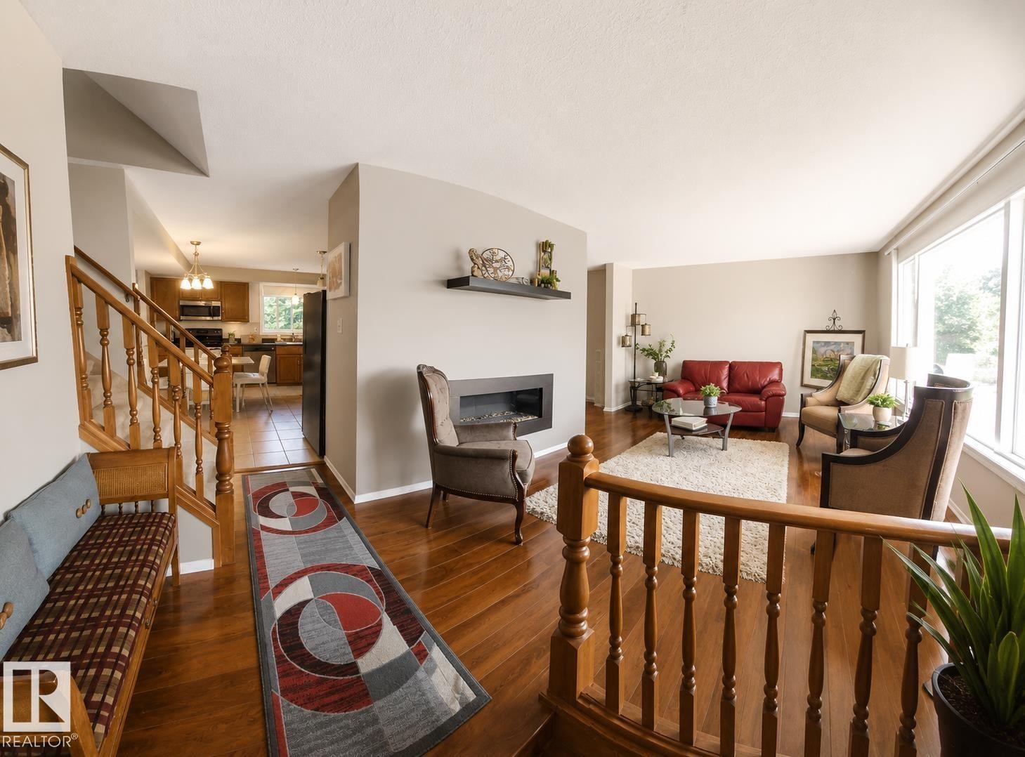 Living area featuring wood-finish flooring, a contemporary wall-mounted fireplace, and large picture windows - 1022 106 Street Nw, Edmonton, AB - Indoor Photo Showing Other Room With Fireplace