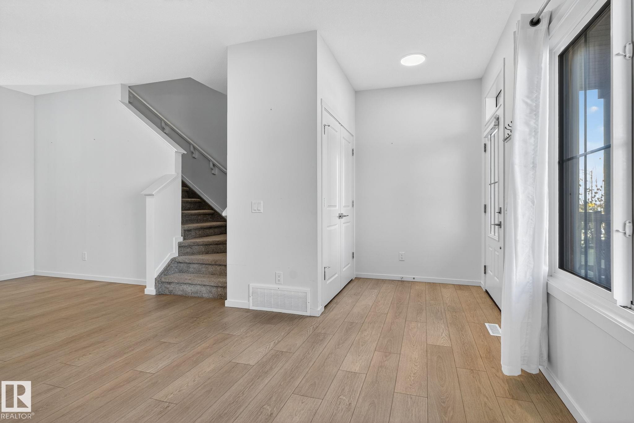 Entryway featuring wood-finish flooring, white walls, and a front door with glass panels - 264 Orchards Boulevard Sw, Edmonton, AB - Indoor Photo Showing Other Room
