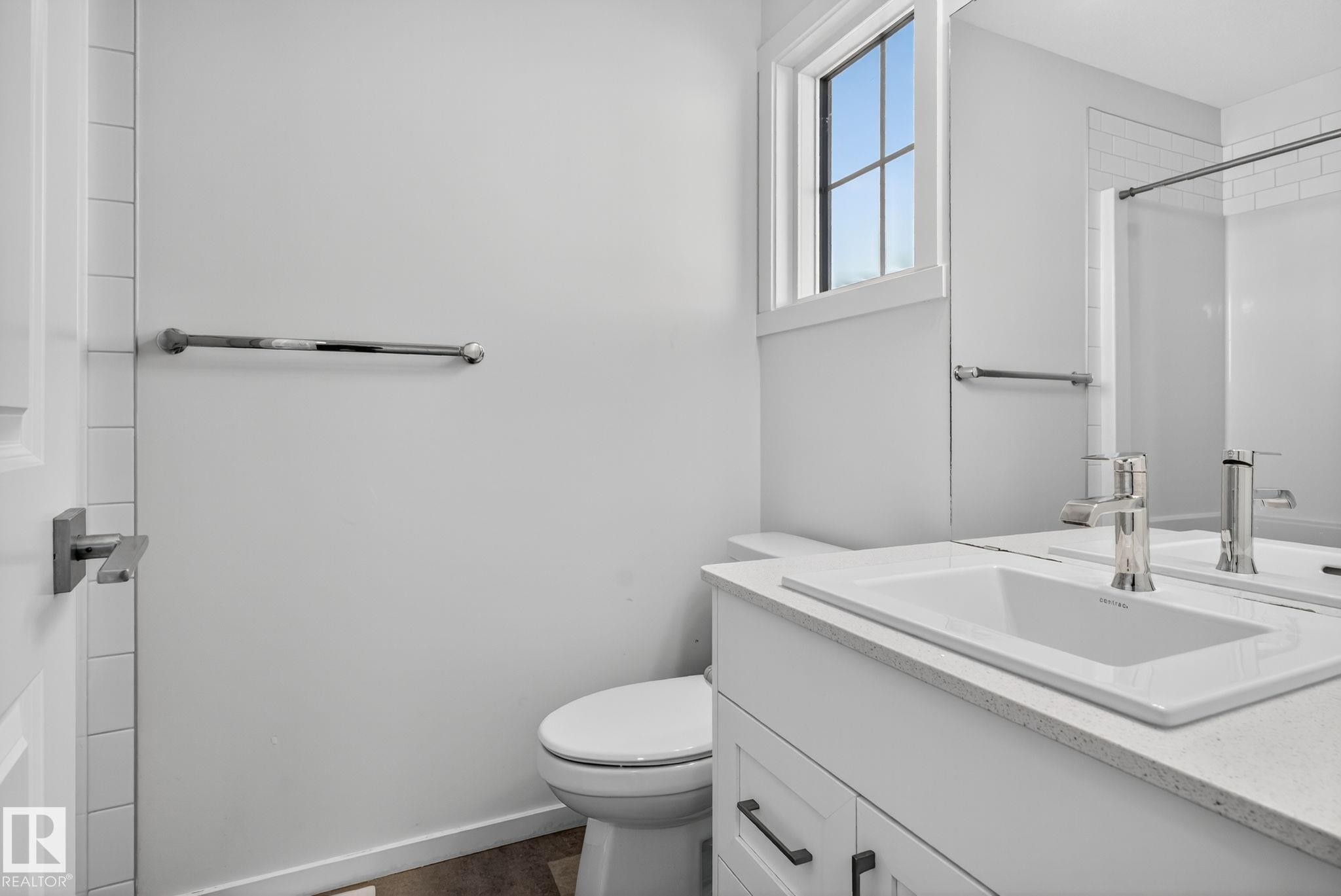 Bathroom featuring a white vanity with an integrated sink, polished chrome faucet, square-edged countertop, and dark cabinet hardware - 264 Orchards Boulevard Sw, Edmonton, AB - Indoor Photo Showing Bathroom