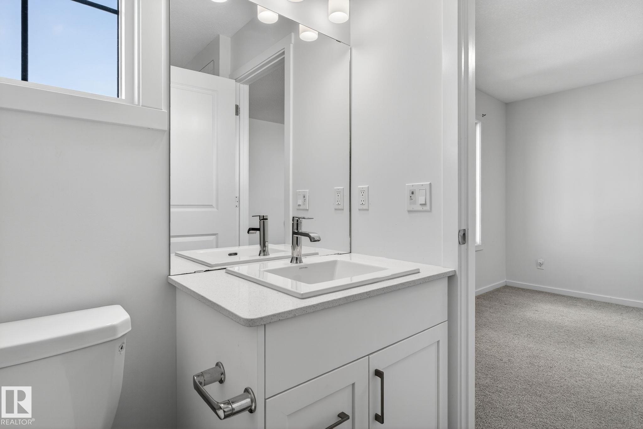 Modern bathroom vanity with integrated sink, stone-finish countertop, and chrome fixtures - 264 Orchards Boulevard Sw, Edmonton, AB - Indoor Photo Showing Bathroom