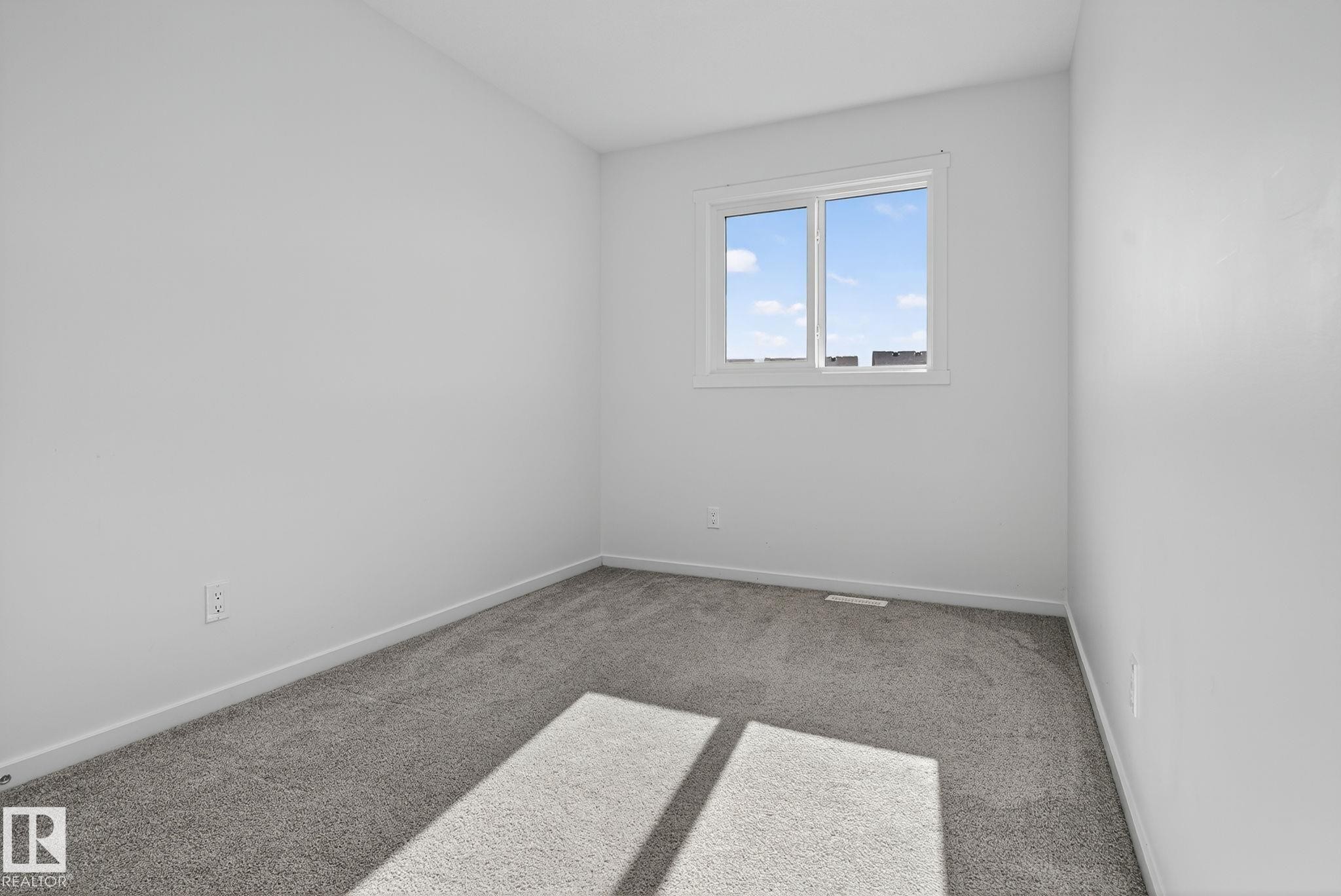 Neutral-toned room featuring a single window and plush gray carpeting - 264 Orchards Boulevard Sw, Edmonton, AB - Indoor Photo Showing Other Room