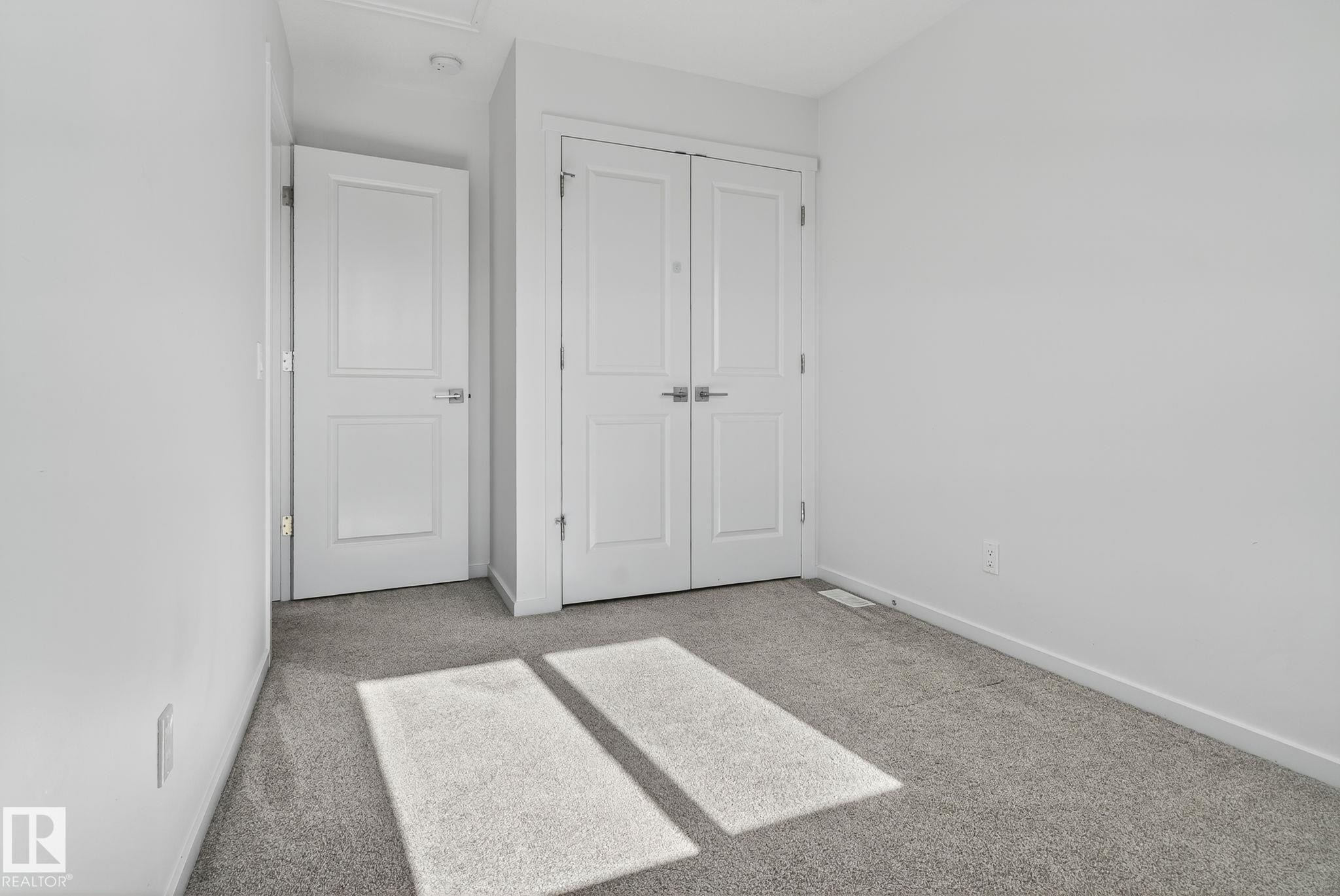 Clean, neutral-toned room featuring light gray carpeting, crisp white walls, and bright white trim - 264 Orchards Boulevard Sw, Edmonton, AB - Indoor Photo Showing Other Room