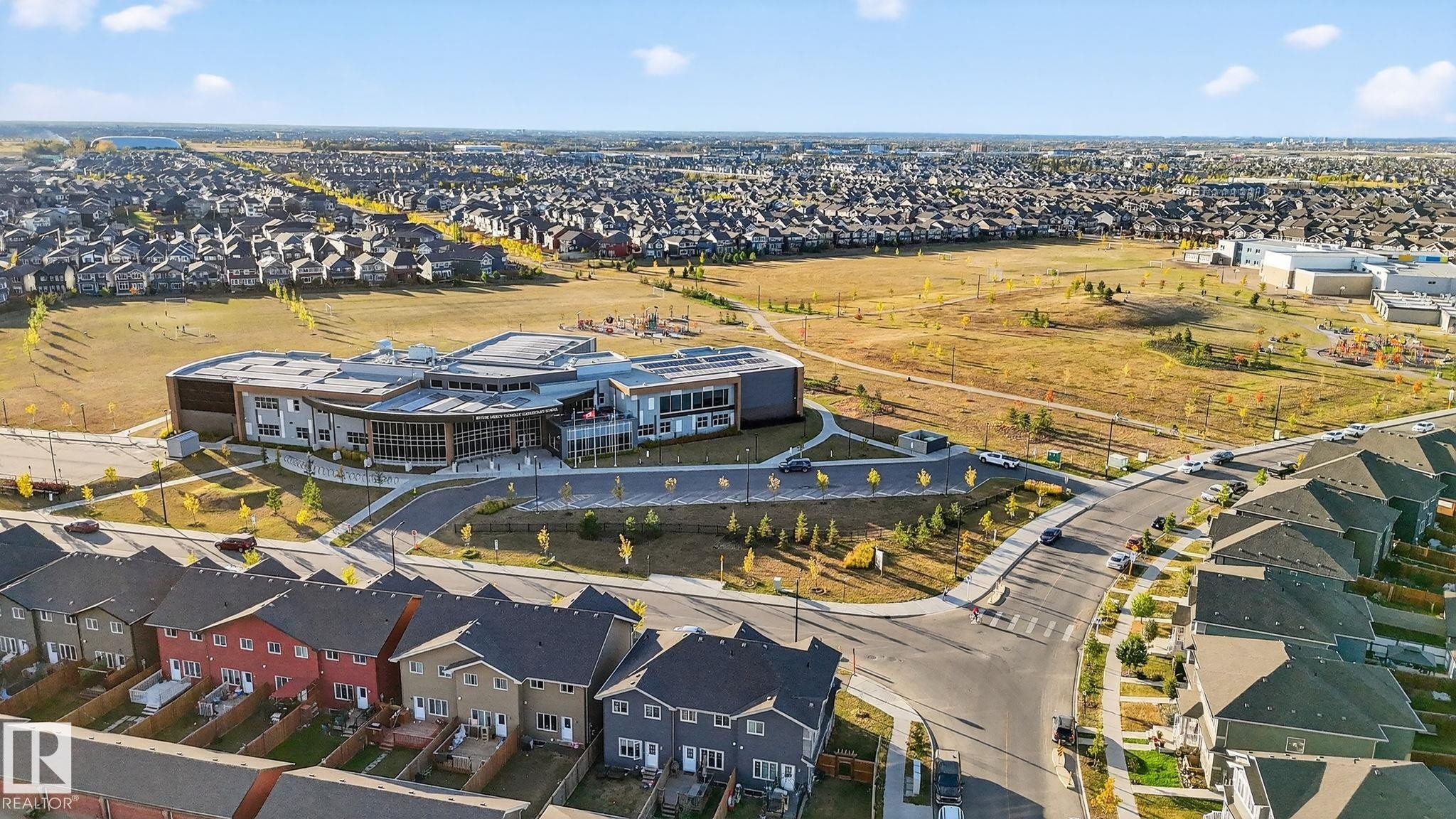 Contemporary building with an expansive playing field and surrounding residential properties - 264 Orchards Boulevard Sw, Edmonton, AB - Outdoor With View