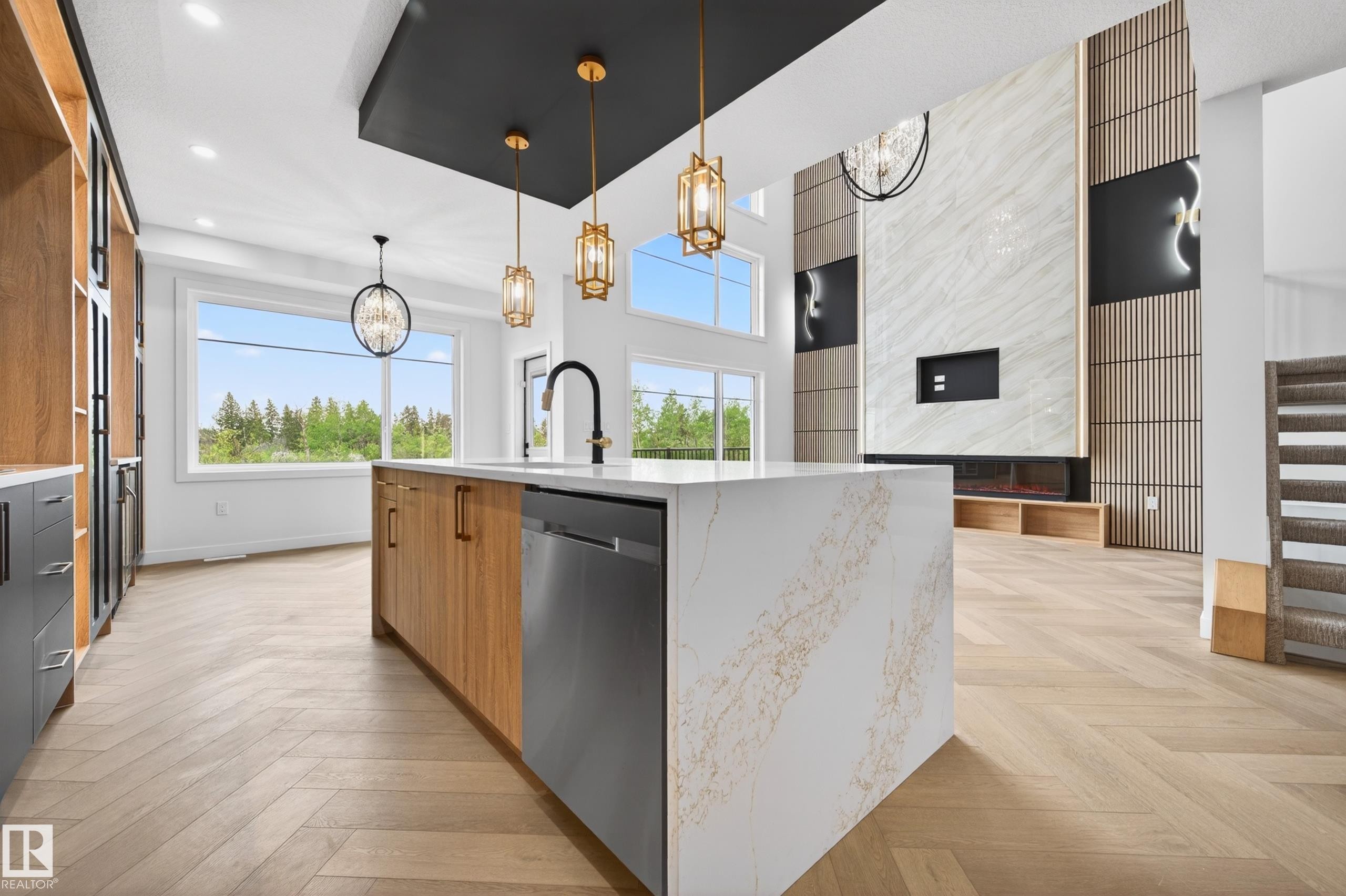 Gourmet kitchen featuring a waterfall island with stone countertops and integrated dishwasher, herringbone wood-finish flooring, and contemporary pendant lighting - 431 172 Avenue, Edmonton, AB - Indoor Photo Showing Kitchen With Upgraded Kitchen
