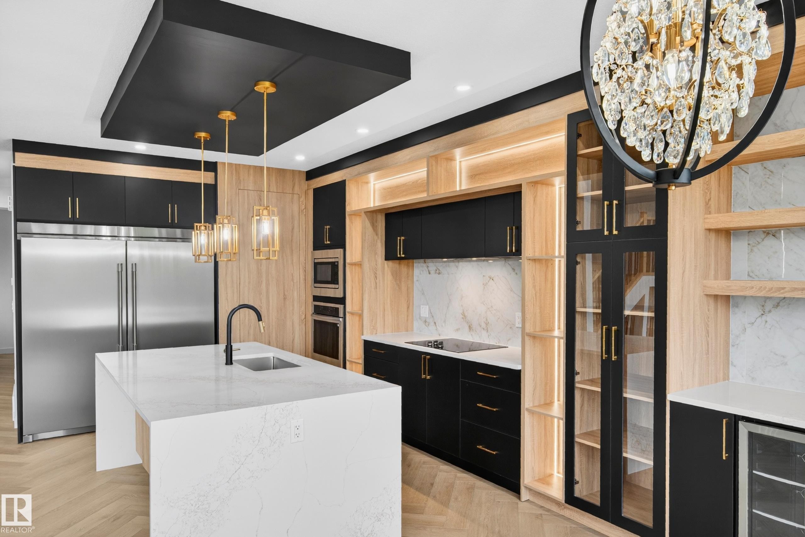 Gourmet kitchen featuring a waterfall island with an undermount sink, stainless steel appliances, black and wood-finish cabinetry, and a large crystal chandelier - 431 172 Avenue, Edmonton, AB - Indoor Photo Showing Kitchen With Upgraded Kitchen
