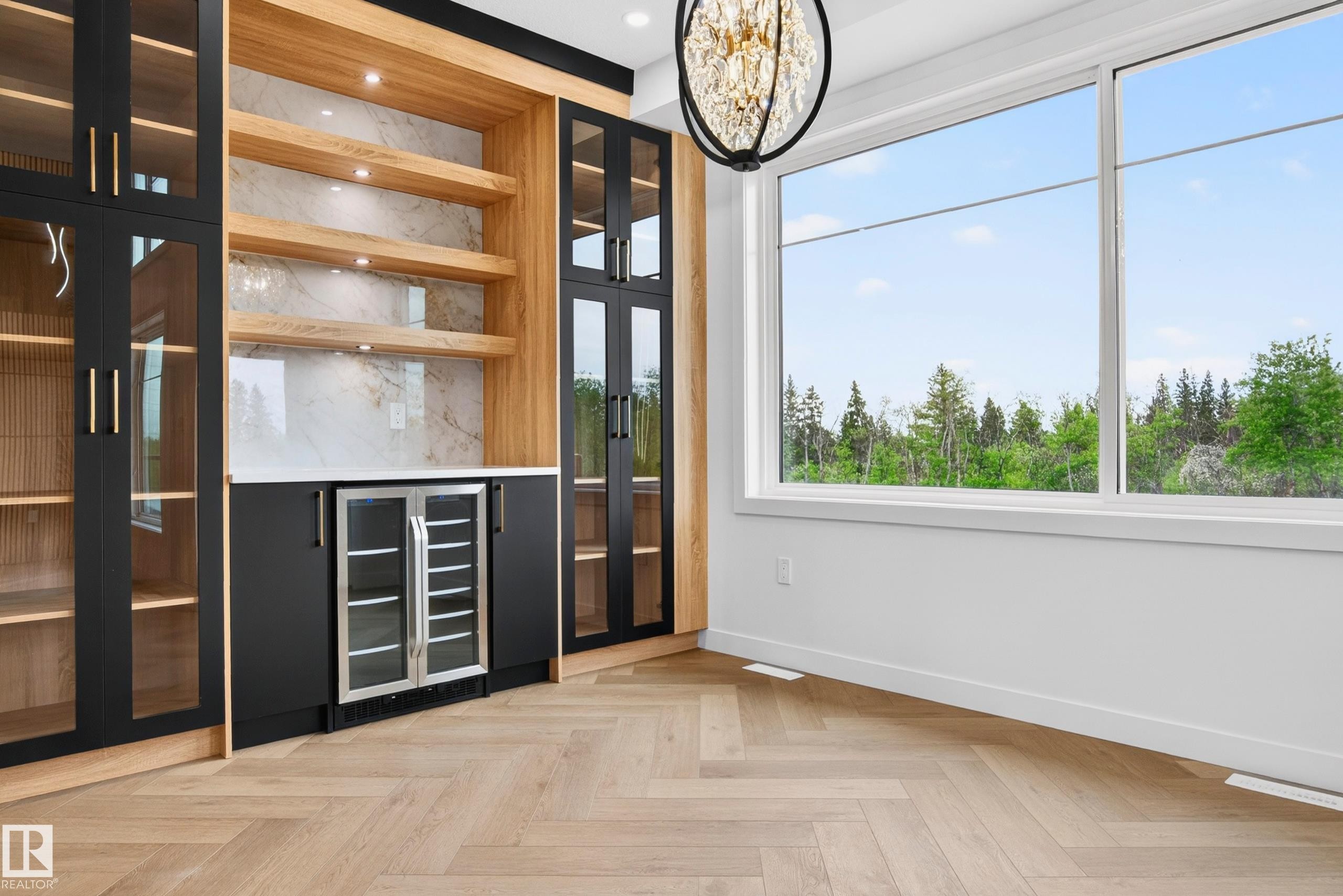 Custom built-in cabinetry featuring black glass-front doors with gold-toned hardware, wood-finish shelving, and a beverage cooler - 431 172 Avenue, Edmonton, AB - Indoor Photo Showing Other Room