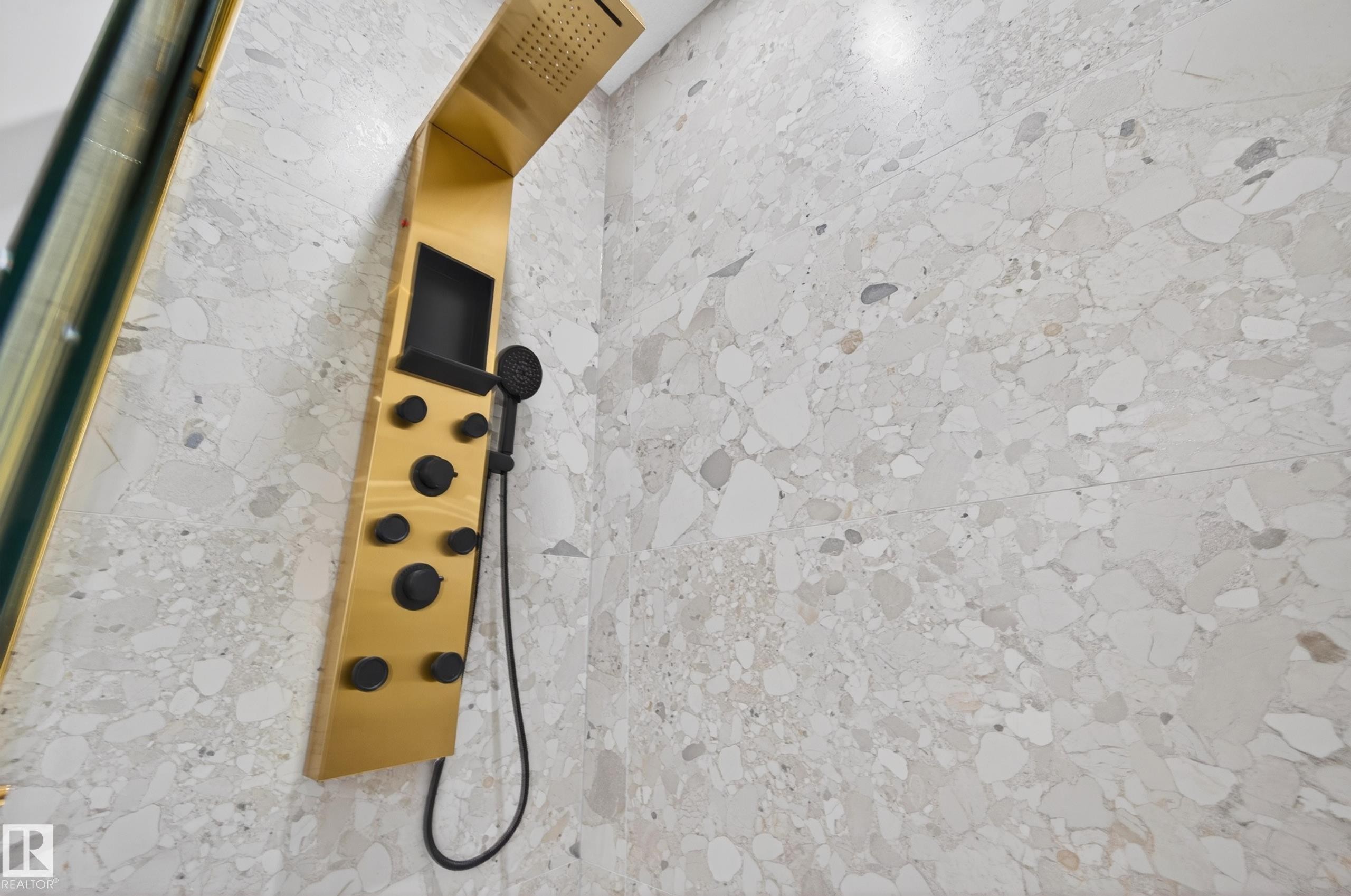Shower enclosure featuring a gold-toned shower panel with multiple body sprays, a handheld shower fixture, and a built-in overhead rain shower - 431 172 Avenue, Edmonton, AB -