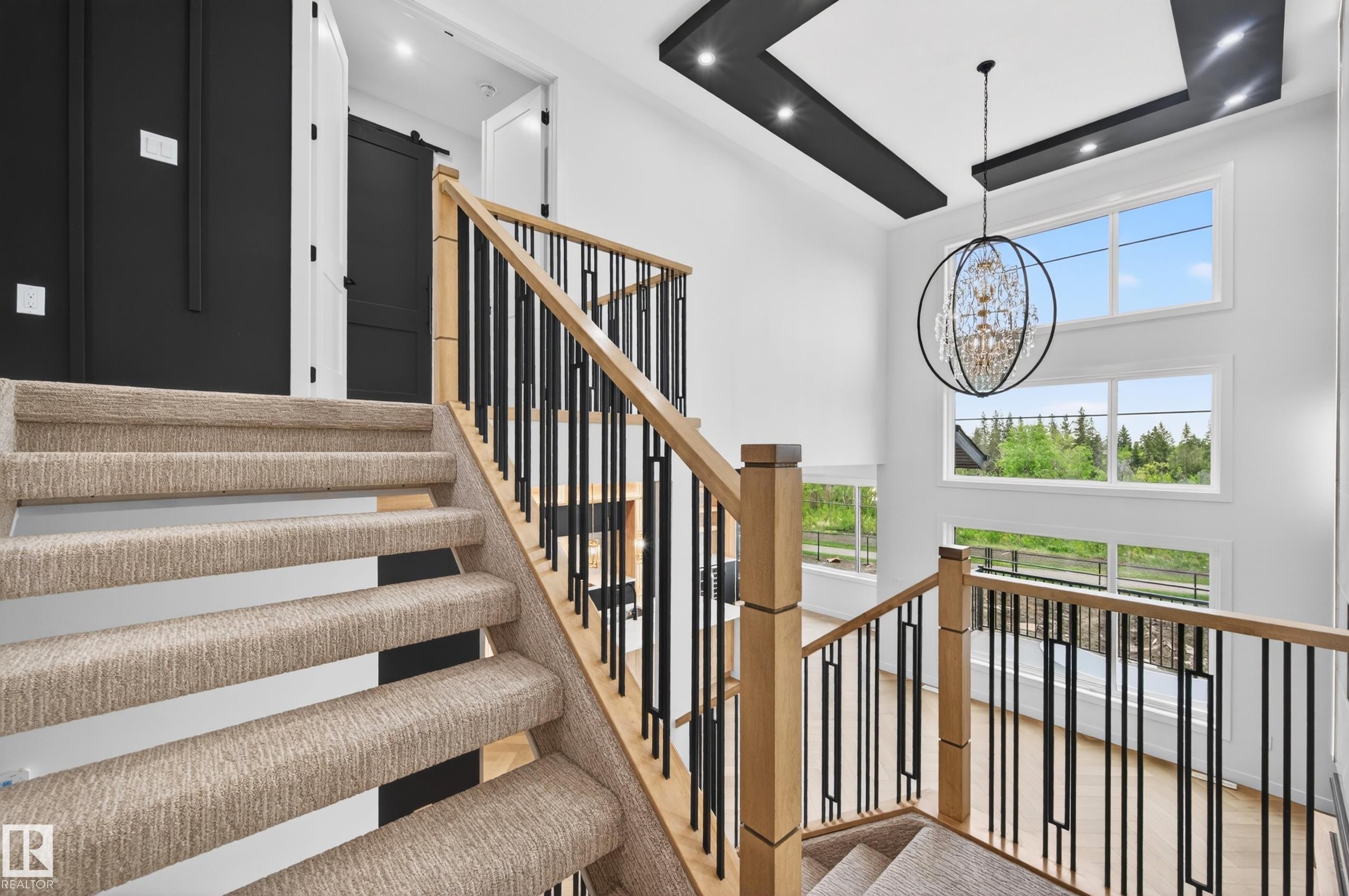 Multi-level staircase featuring carpeted treads and natural wood handrails with black metal balusters - 431 172 Avenue, Edmonton, AB - Indoor Photo Showing Other Room