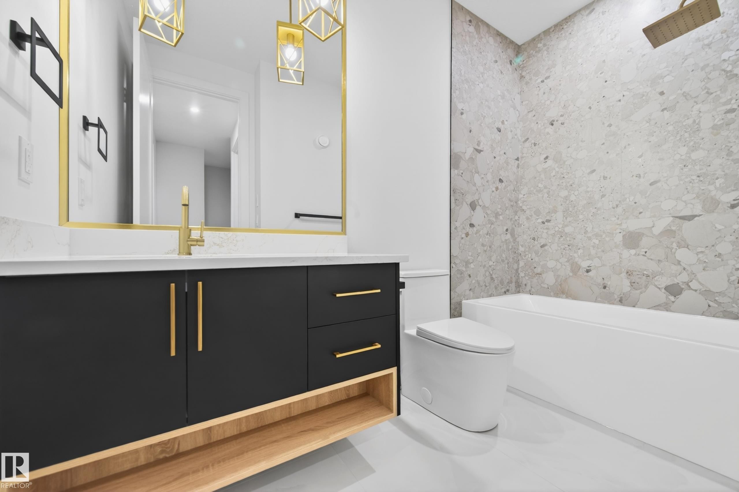 Contemporary bathroom featuring a black vanity with gold hardware, a white countertop, and a rectangular gold-framed mirror - 431 172 Avenue, Edmonton, AB - Indoor Photo Showing Bathroom
