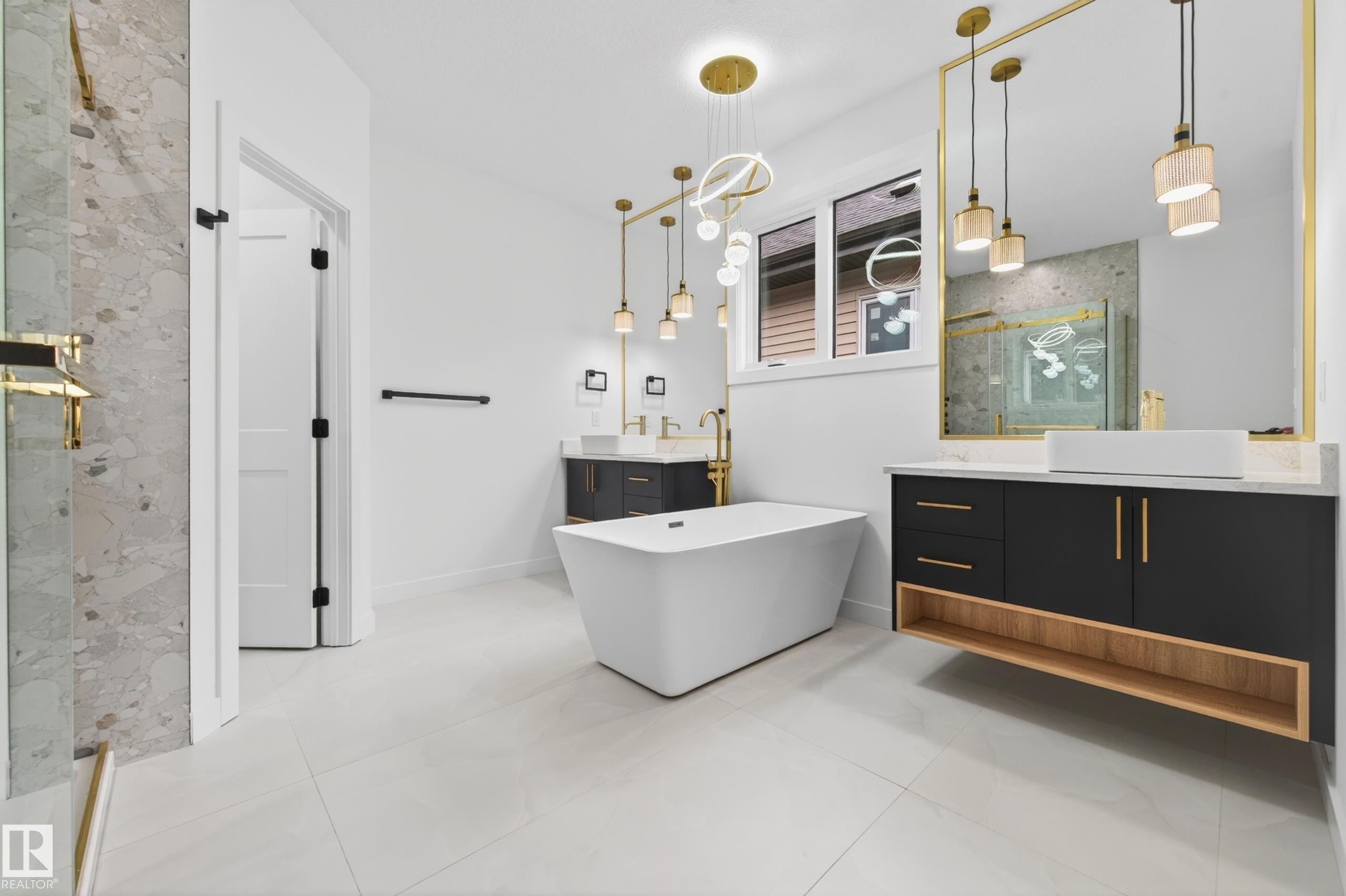 Spacious bathroom featuring a freestanding soaking tub, dual floating vanities with vessel sinks, a large mirror with gold-tone framing, and tiled flooring - 431 172 Avenue, Edmonton, AB - Indoor Photo Showing Bathroom