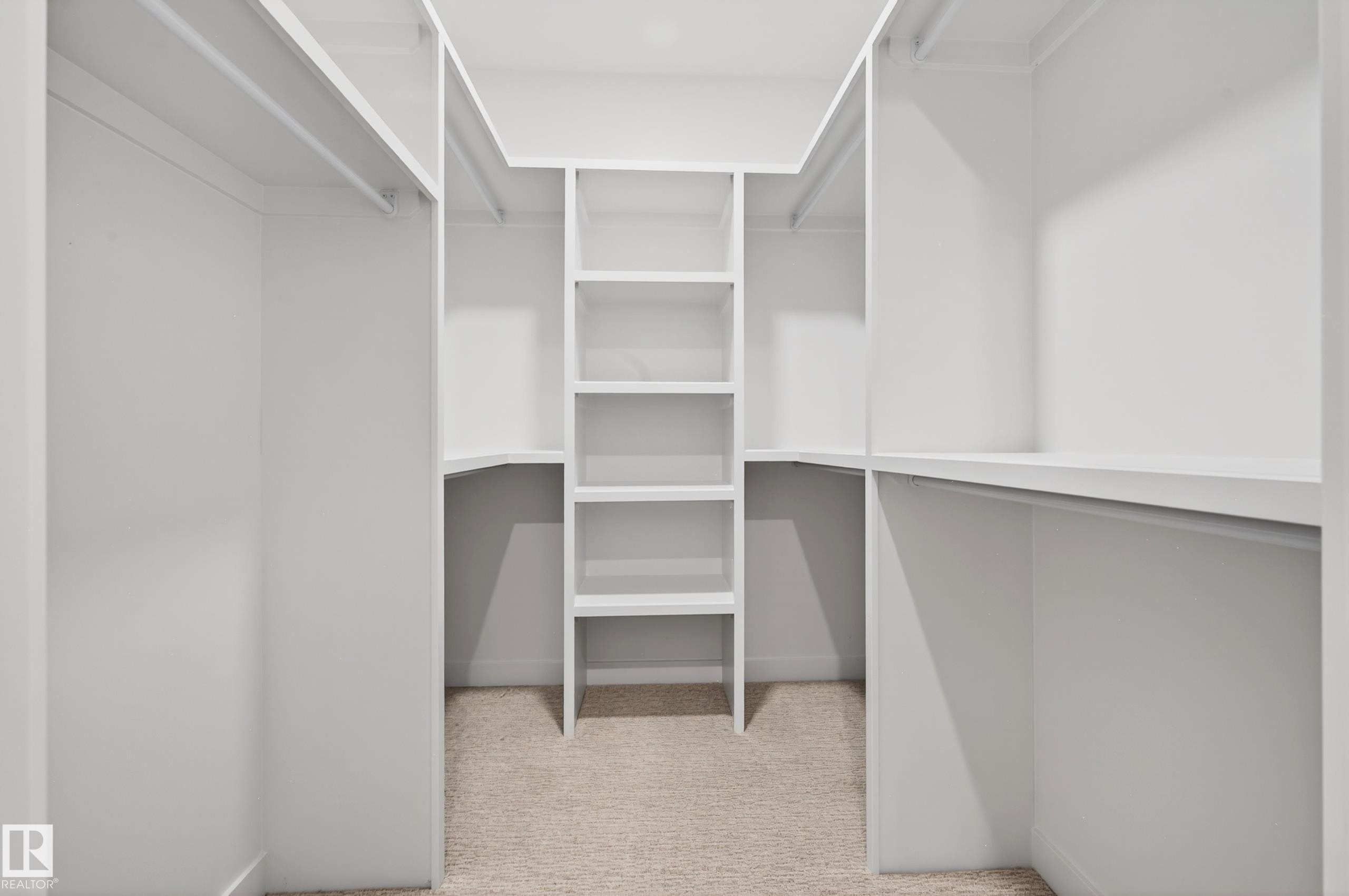 Walk-in closet featuring white built-in shelving, multiple hanging rods, and light-toned carpet flooring - 431 172 Avenue, Edmonton, AB - Indoor With Storage