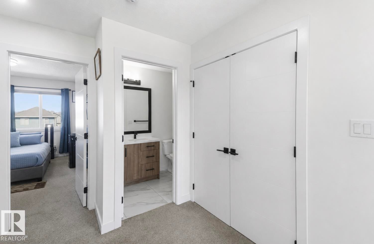 Hallway featuring plush carpet flooring, white walls, and contemporary black hardware on doors - 17924 61 Street Nw, Edmonton, AB - Indoor