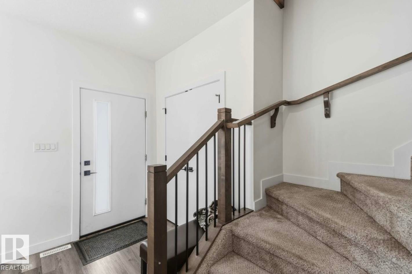 Entryway featuring a contemporary white door with frosted glass panel, matte black hardware, and wood-finish flooring - 17924 61 Street Nw, Edmonton, AB - Indoor Photo Showing Other Room