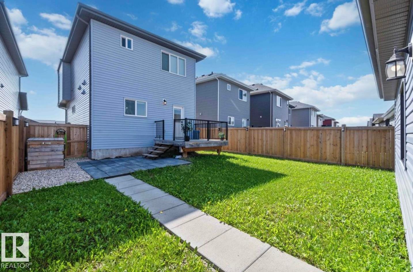 Expansive rear yard featuring a wooden privacy fence, a concrete paver walkway, and a gravel accent area - 17924 61 Street Nw, Edmonton, AB - Outdoor