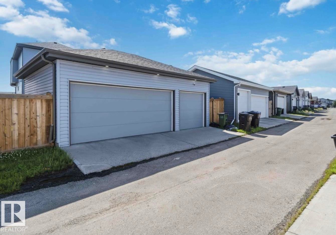 Two-car garage with light gray overhead doors, light gray siding, and a concrete driveway - 17924 61 Street Nw, Edmonton, AB - Outdoor