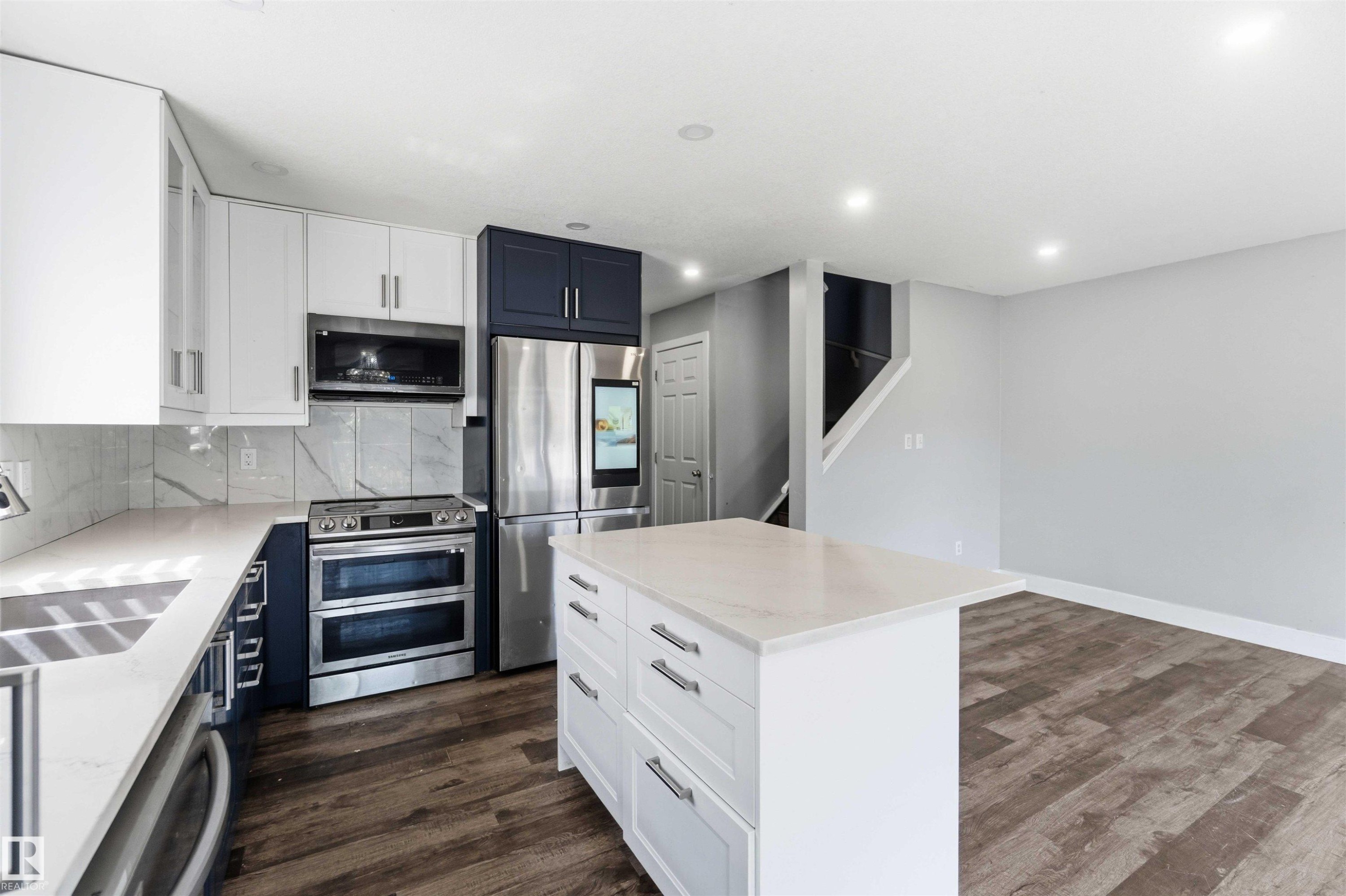 Modern kitchen featuring stainless steel appliances, including a French-door refrigerator, dual ovens, and gas cooktop - #64 120 Magrath Rd Nw, Edmonton, AB - Indoor Photo Showing Kitchen With Double Sink With Upgraded Kitchen