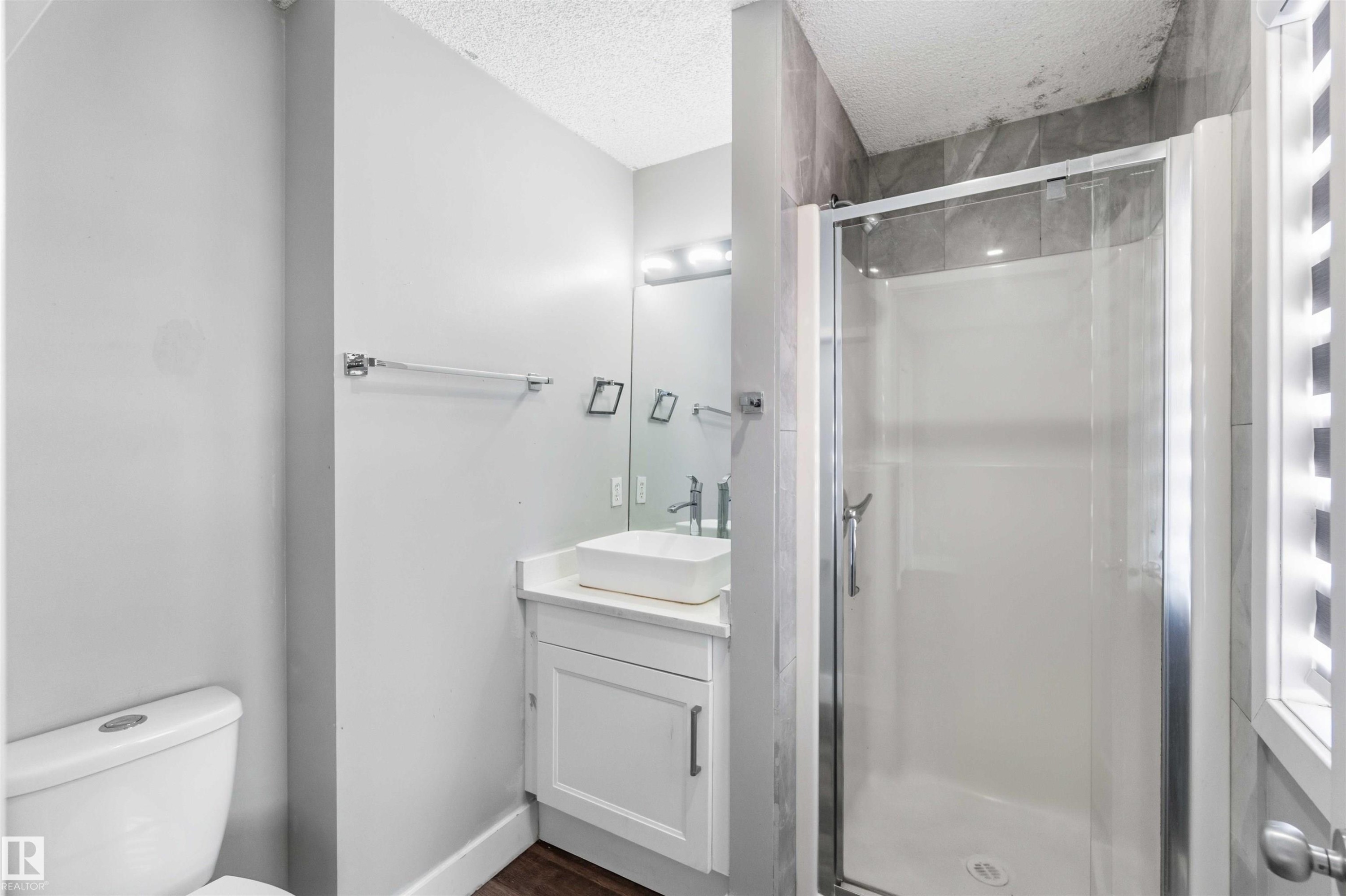 Modern bathroom featuring a glass-enclosed shower with tile surround, white floating vanity with vessel sink, and chrome fixtures - #64 120 Magrath Rd Nw, Edmonton, AB - Indoor Photo Showing Bathroom