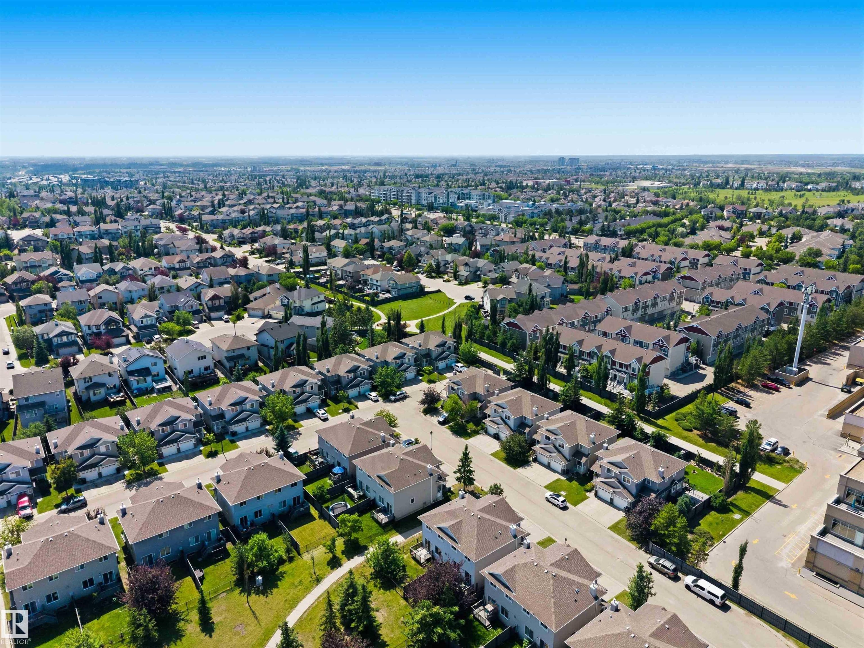 Aerial perspective showcasing a residential development with detached homes and multi-family buildings - #64 120 Magrath Rd Nw, Edmonton, AB - Outdoor With View