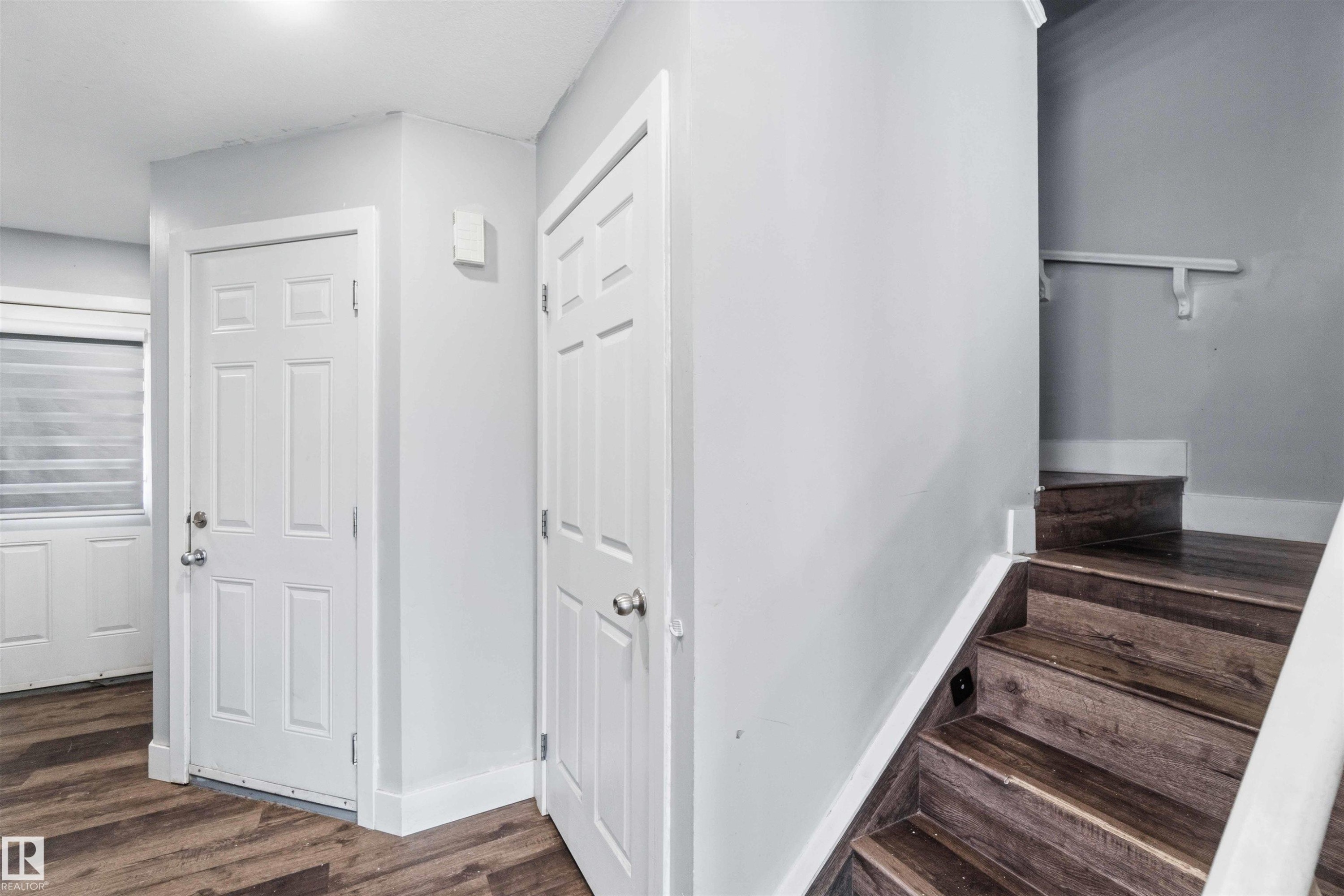 Entryway featuring wood-finish flooring, white paneled doors, and a staircase with a matching wood-finish - #64 120 Magrath Rd Nw, Edmonton, AB - Indoor Photo Showing Other Room