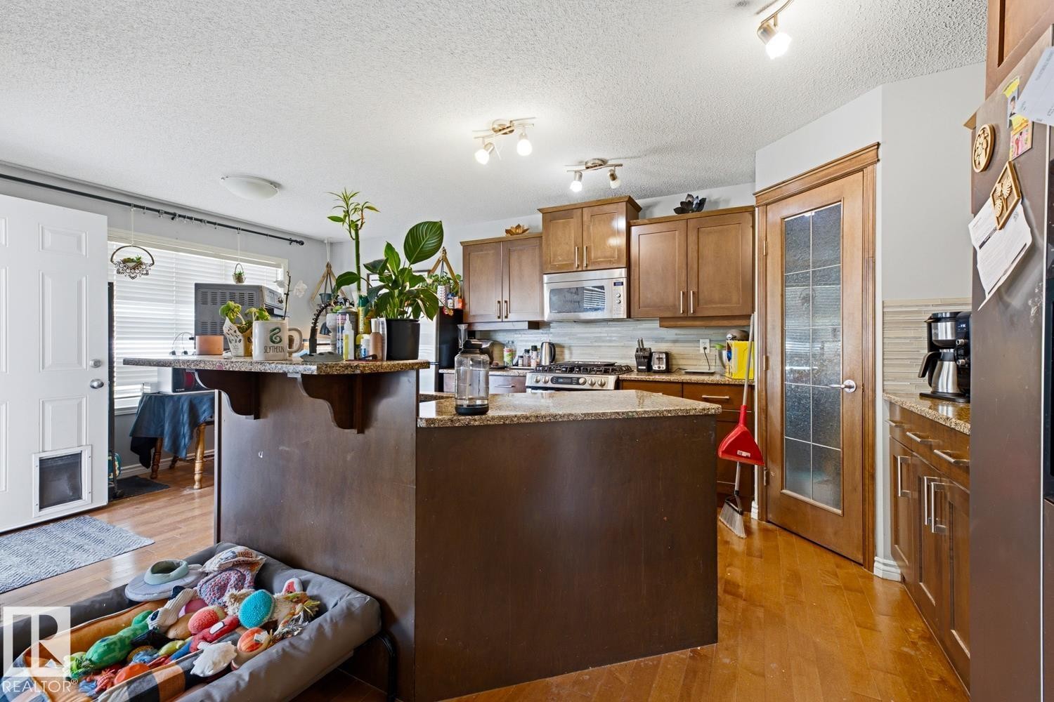 Kitchen featuring wood-finish flooring, wood cabinetry, stone countertops, and stainless steel appliances - 3724 163 Avenue Nw, Edmonton, AB - Indoor Photo Showing Kitchen