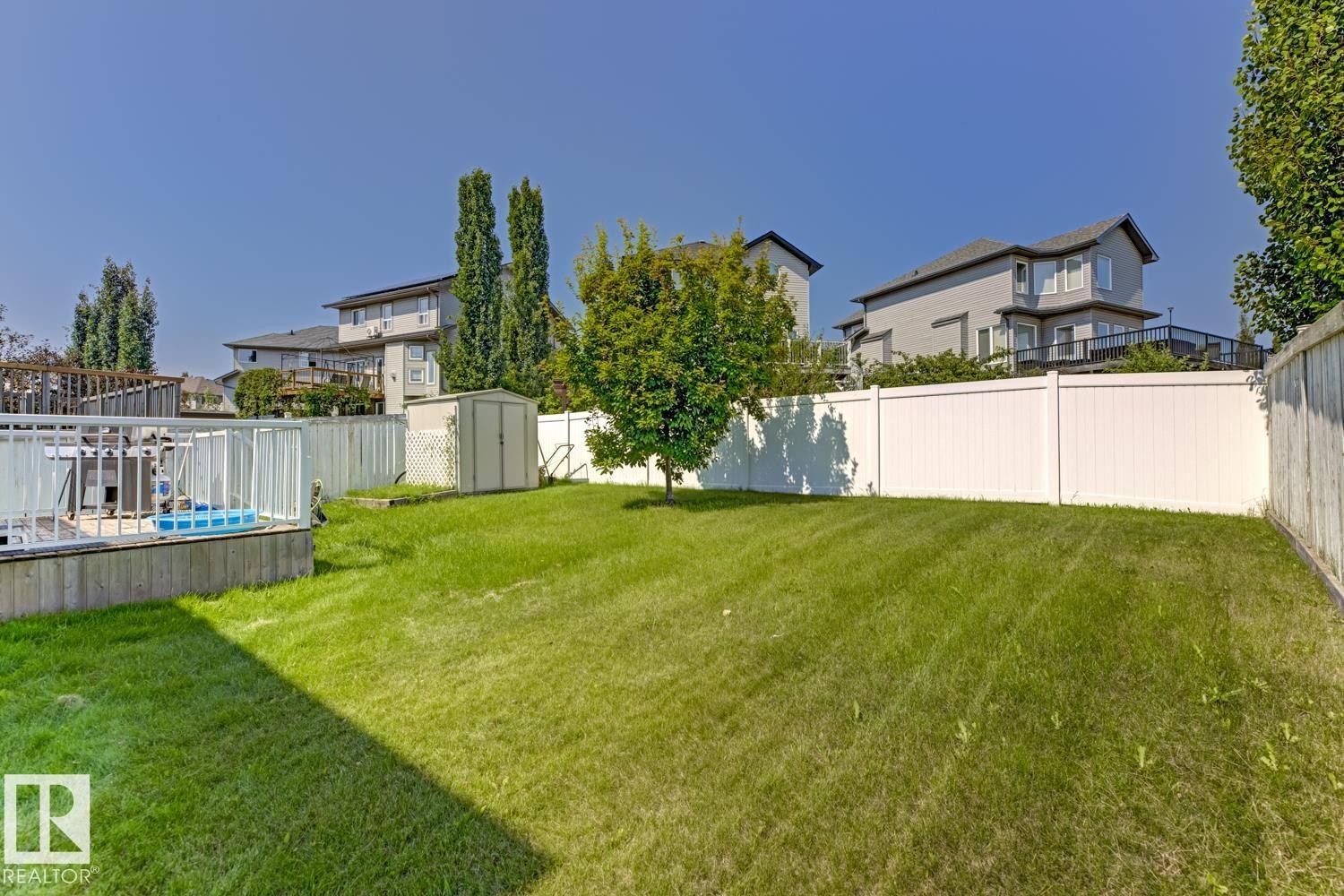 Expansive backyard featuring a manicured lawn, a white privacy fence, and a dedicated storage shed - 3724 163 Avenue Nw, Edmonton, AB - Outdoor With Backyard