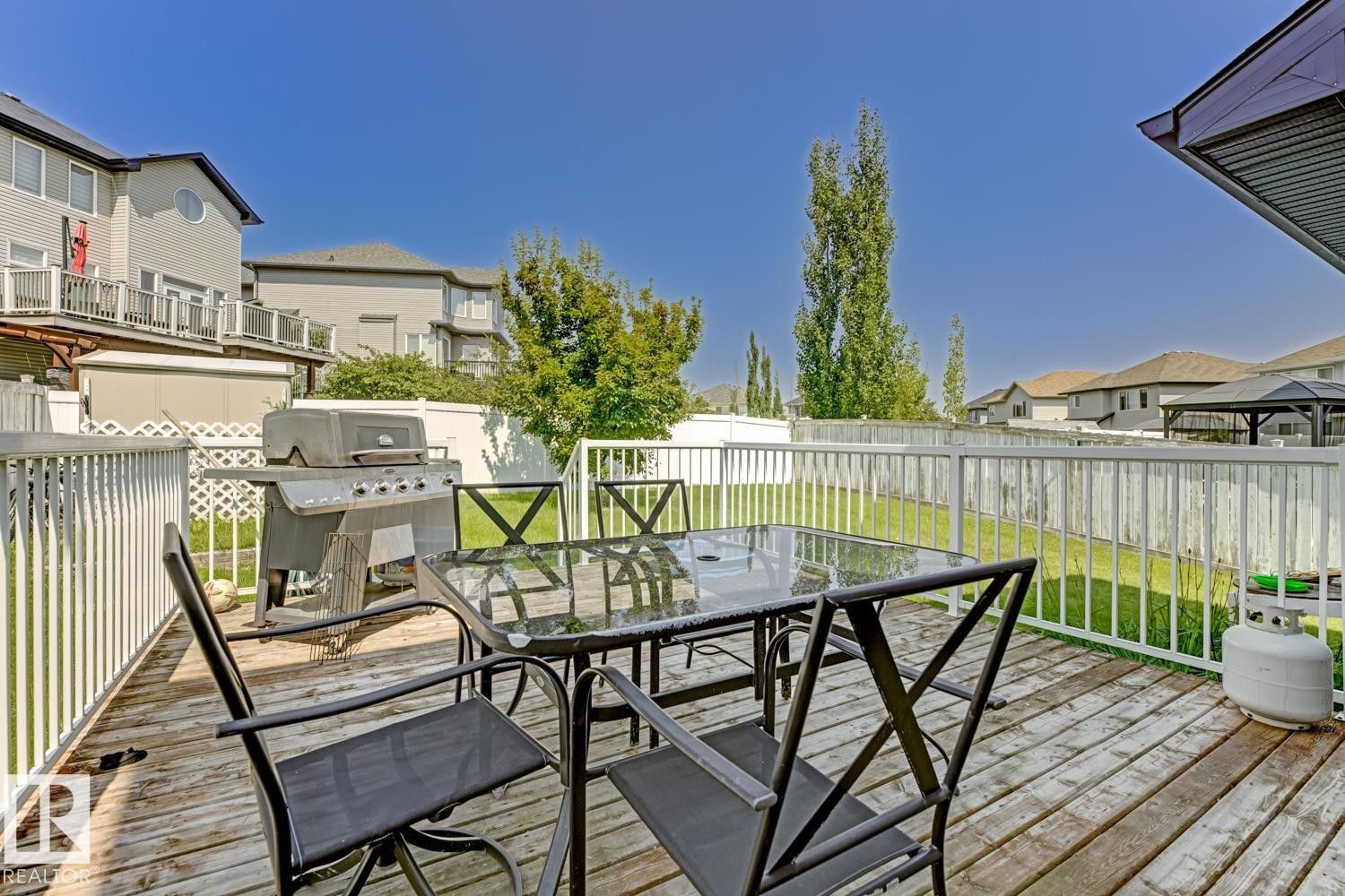 Spacious outdoor deck featuring wood-finish flooring, white railing, and a sizable backyard with a manicured lawn - 3724 163 Avenue Nw, Edmonton, AB - Outdoor With Deck Patio Veranda With Exterior