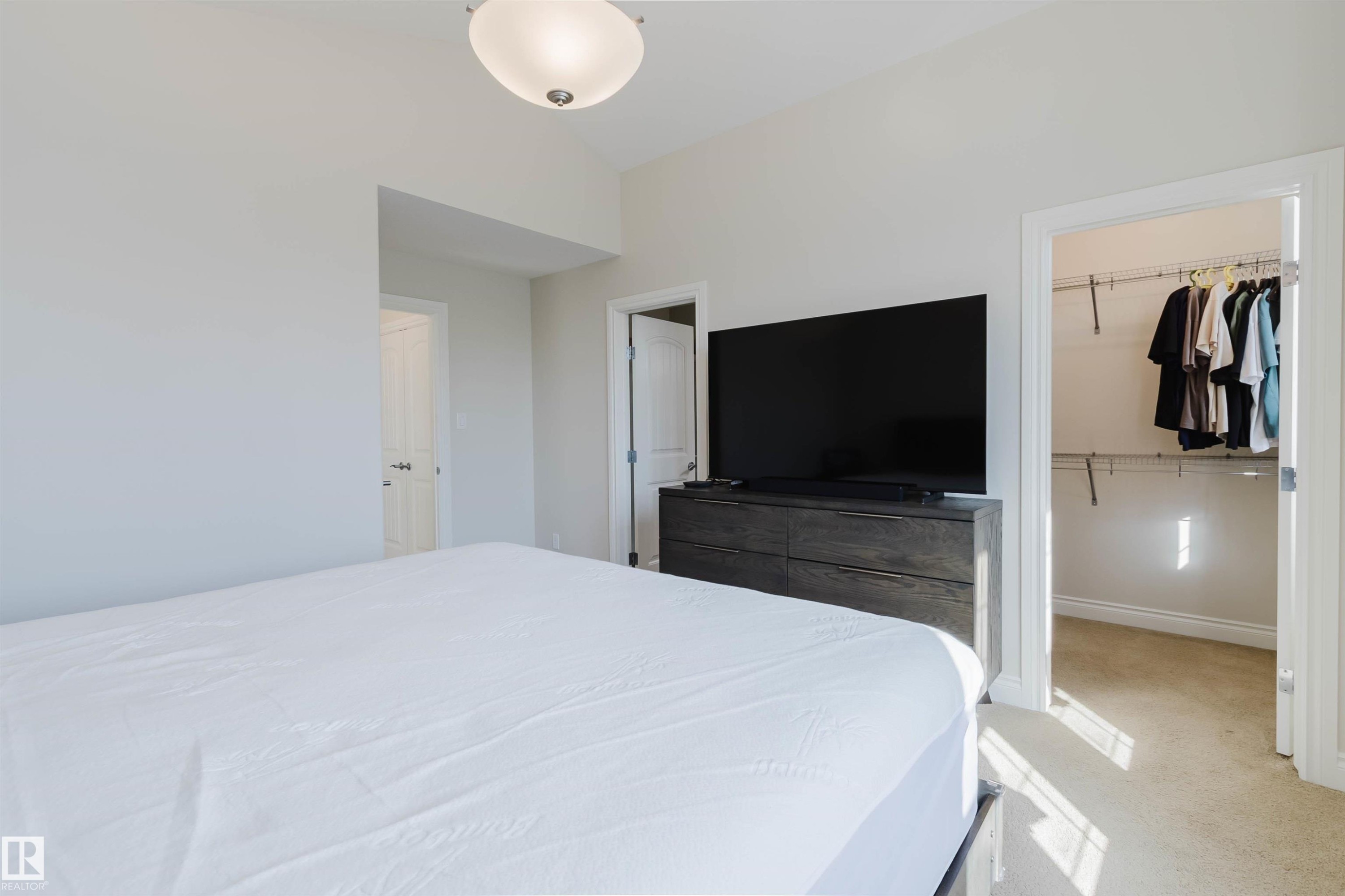 Bedroom featuring light neutral wall paint, a built-in closet with wire shelving, carpet flooring, and a flush-mount ceiling light fixture - 17348 6 Avenue Sw, Edmonton, AB - Indoor Photo Showing Bedroom