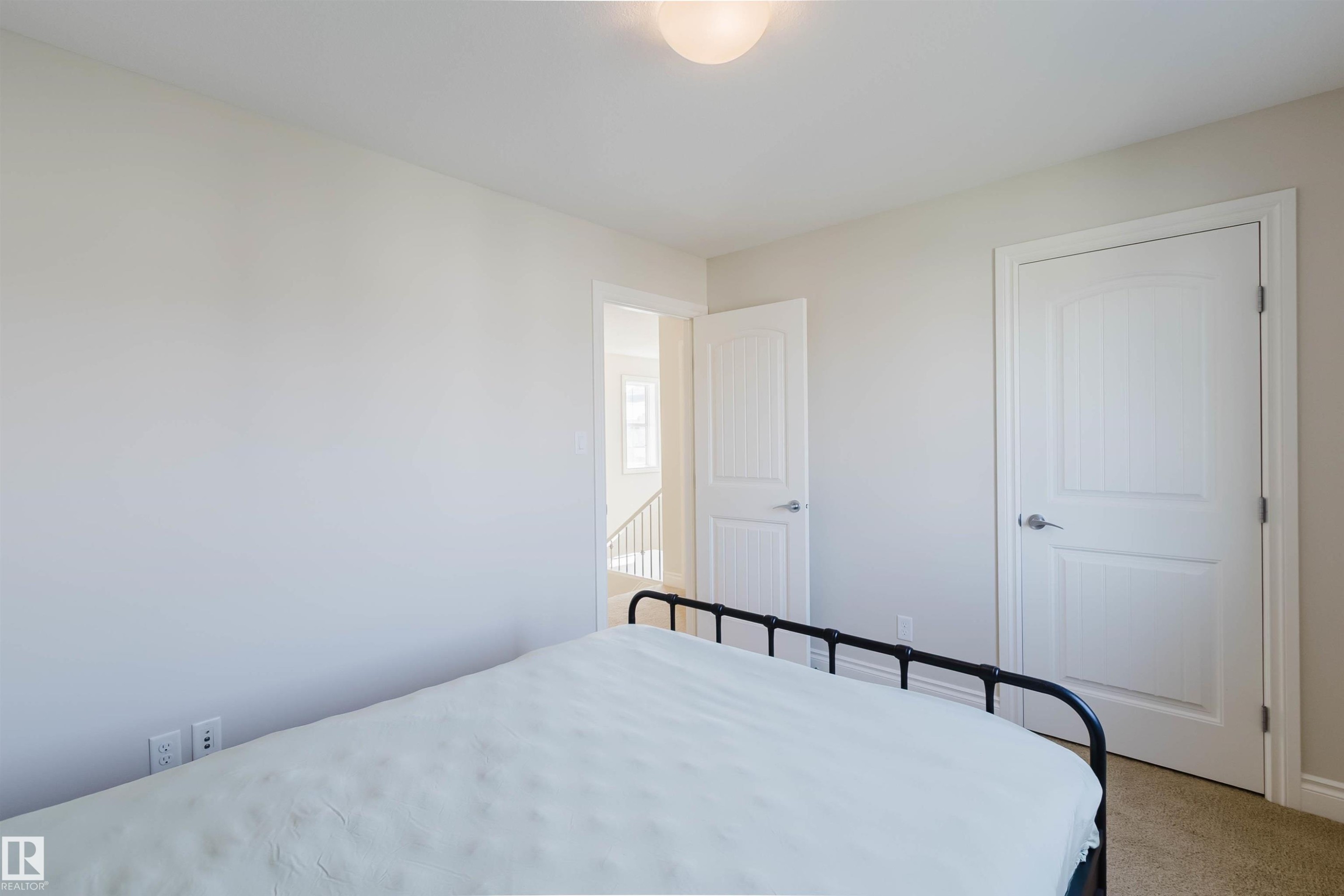 Bedroom featuring light neutral paint, carpet flooring, a flush-mount ceiling light, and white paneled doors with brushed nickel hardware - 17348 6 Avenue Sw, Edmonton, AB - Indoor Photo Showing Bedroom