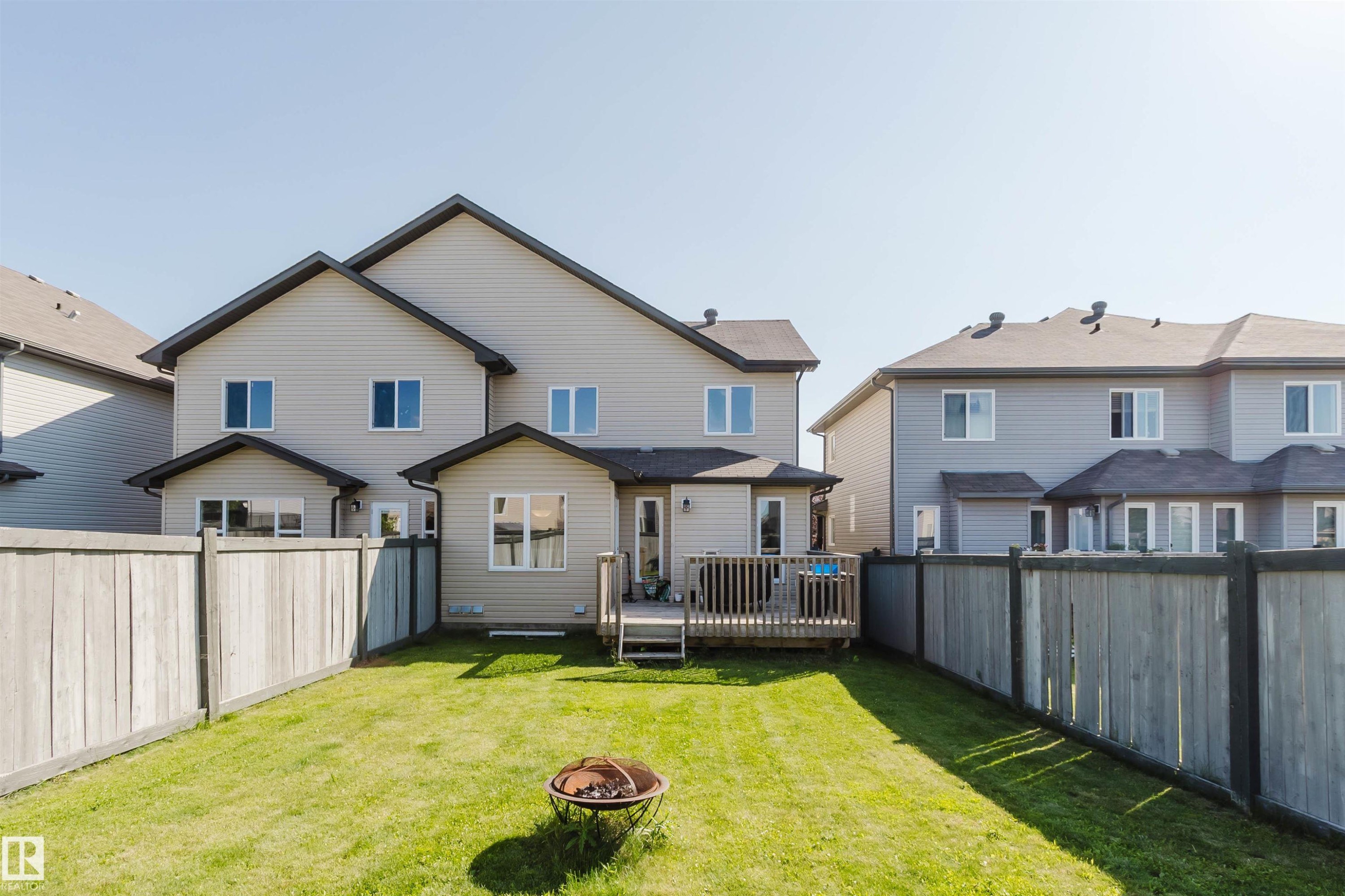 Expansive backyard featuring a manicured lawn, full wood fencing, and a multi-level wood deck - 17348 6 Avenue Sw, Edmonton, AB - Outdoor With Deck Patio Veranda