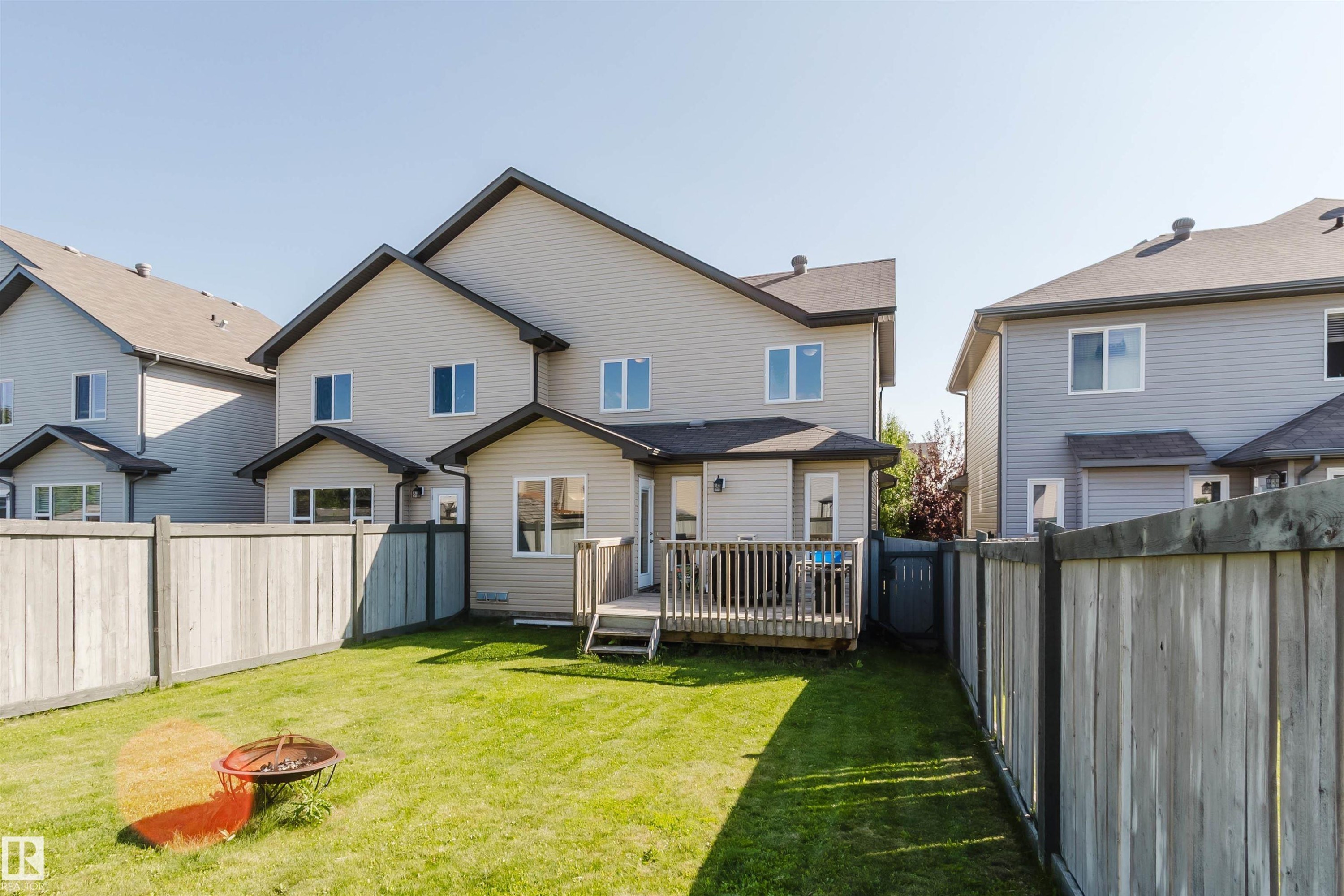 Expansive backyard featuring a manicured lawn, full perimeter fencing, and a wooden deck - 17348 6 Avenue Sw, Edmonton, AB - Outdoor With Deck Patio Veranda
