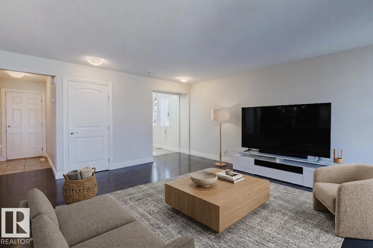 Interior space featuring dark wood-finish flooring, light-toned walls, white trim, and flush-mount lighting fixtures - 17348 6 Avenue Sw, Edmonton, AB - Indoor Photo Showing Living Room
