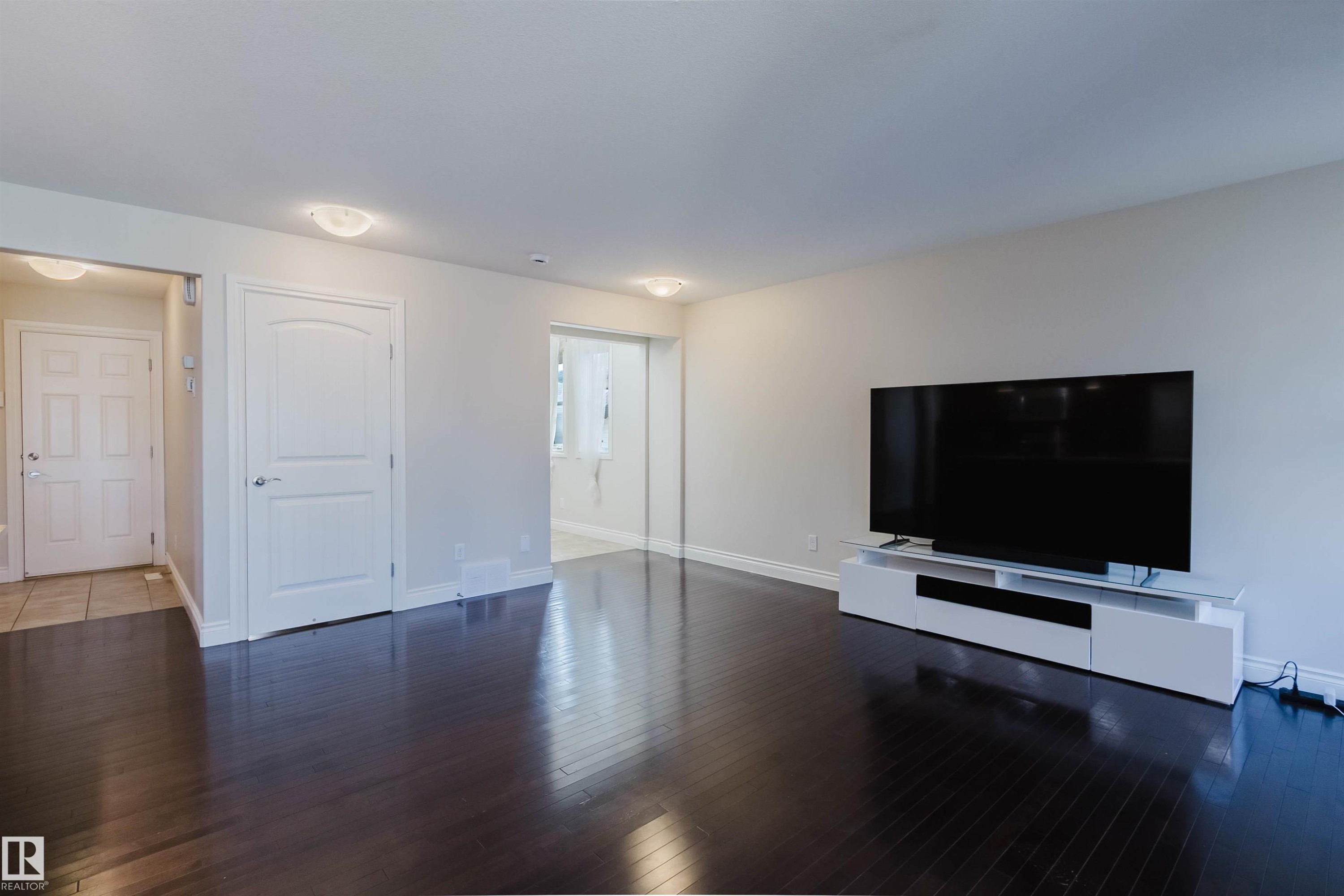 Spacious room featuring dark wood-finish flooring, light-toned walls, and recessed lighting - 17348 6 Avenue Sw, Edmonton, AB - Indoor Photo Showing Living Room