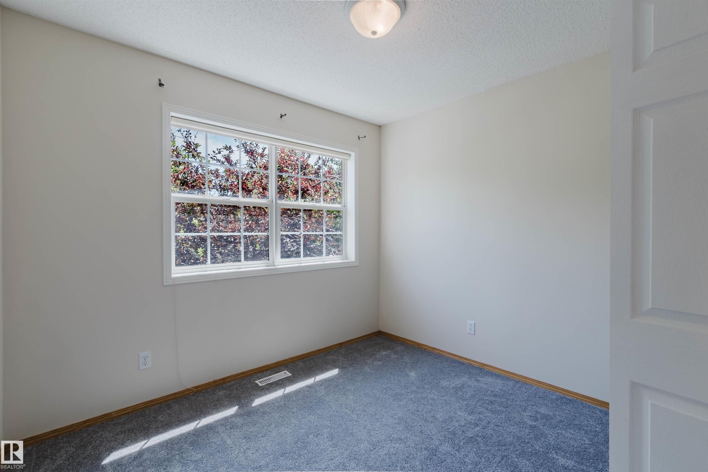 Bright room featuring a large window, neutral wall paint, gray carpet flooring, white trim, and a flush-mount ceiling light fixture - 1686 Tompkins Wynd Nw, Edmonton, AB - Indoor Photo Showing Other Room