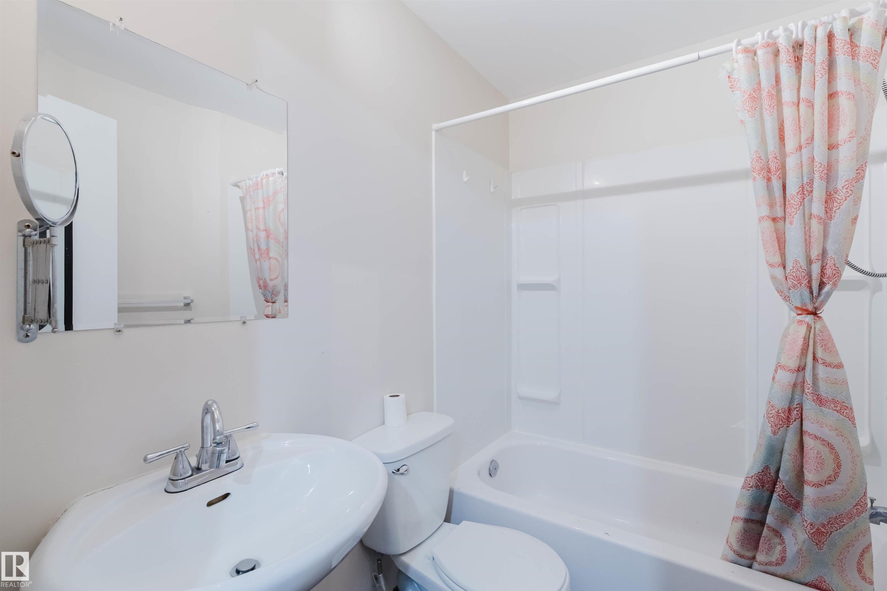Bathroom featuring a white ceramic sink with chrome faucet, a wall-mounted mirror, and a full-size bathtub with an integrated shower - 1686 Tompkins Wynd Nw, Edmonton, AB - Indoor Photo Showing Bathroom
