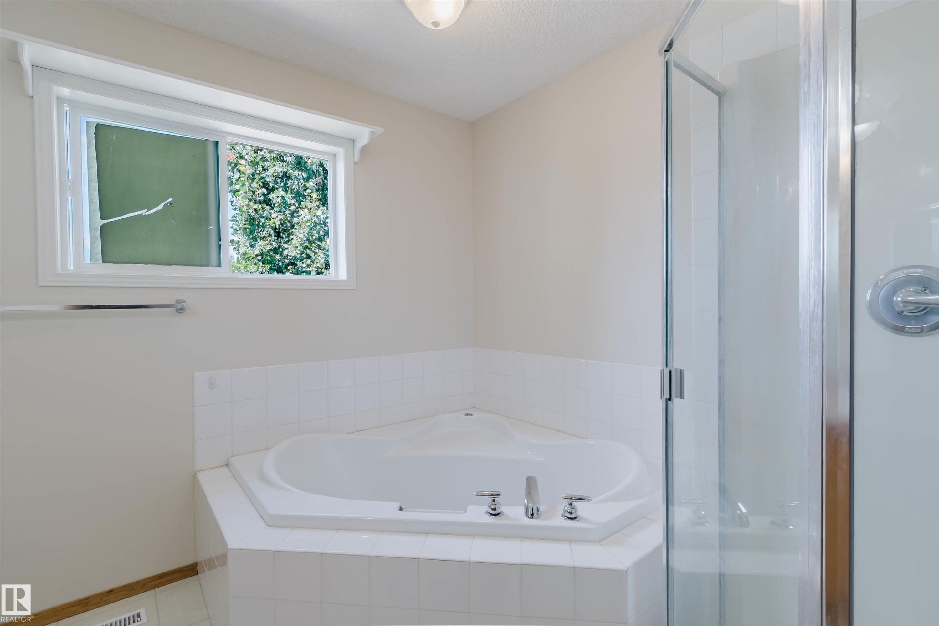 Corner soaking tub with tile surround, framed window, and glass-enclosed shower - 1686 Tompkins Wynd Nw, Edmonton, AB - Indoor Photo Showing Bathroom