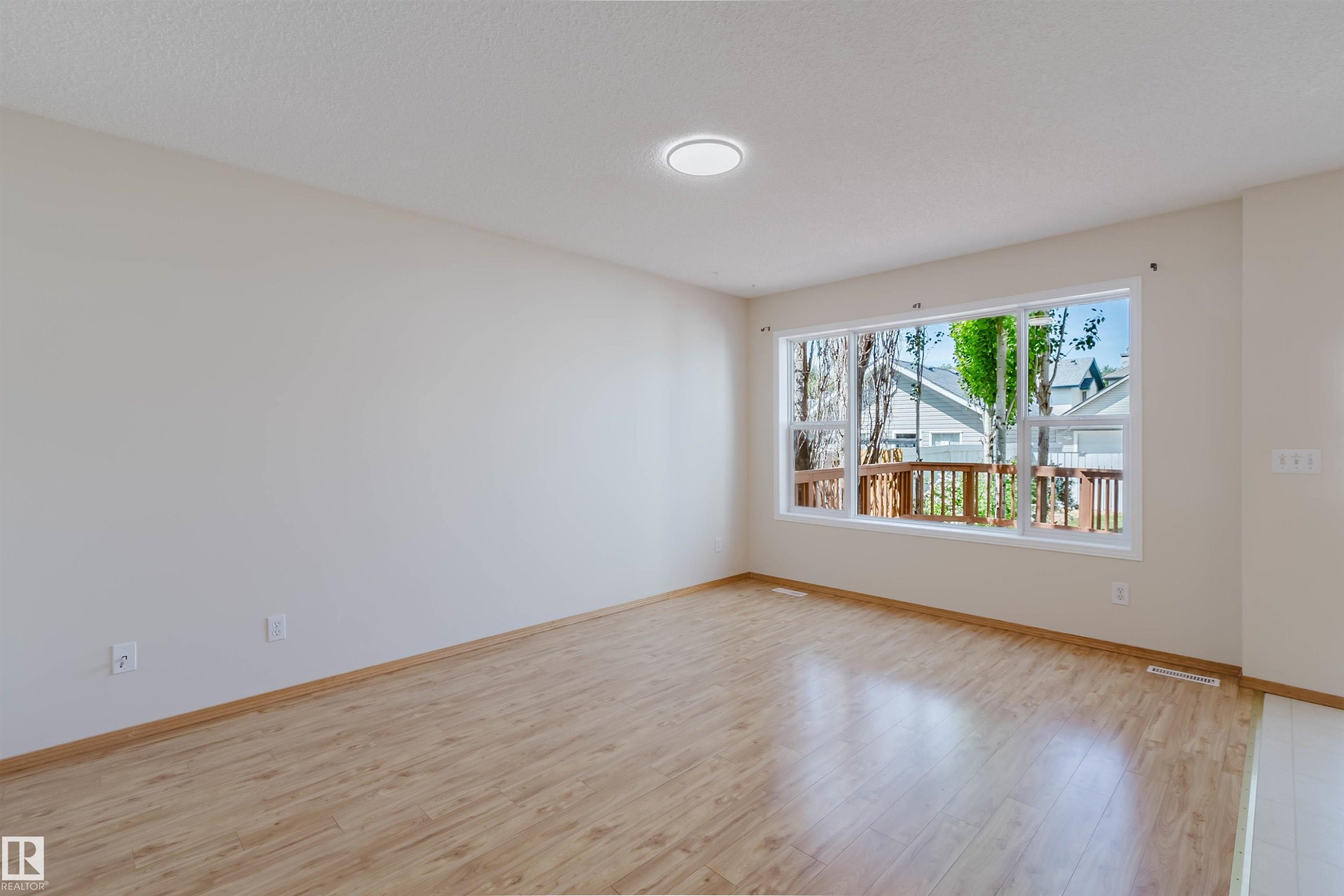 Expansive interior room featuring light wood-finish flooring, a contemporary flush-mount ceiling light, and ample natural light from a large multi-pane window - 1686 Tompkins Wynd Nw, Edmonton, AB - Indoor Photo Showing Other Room