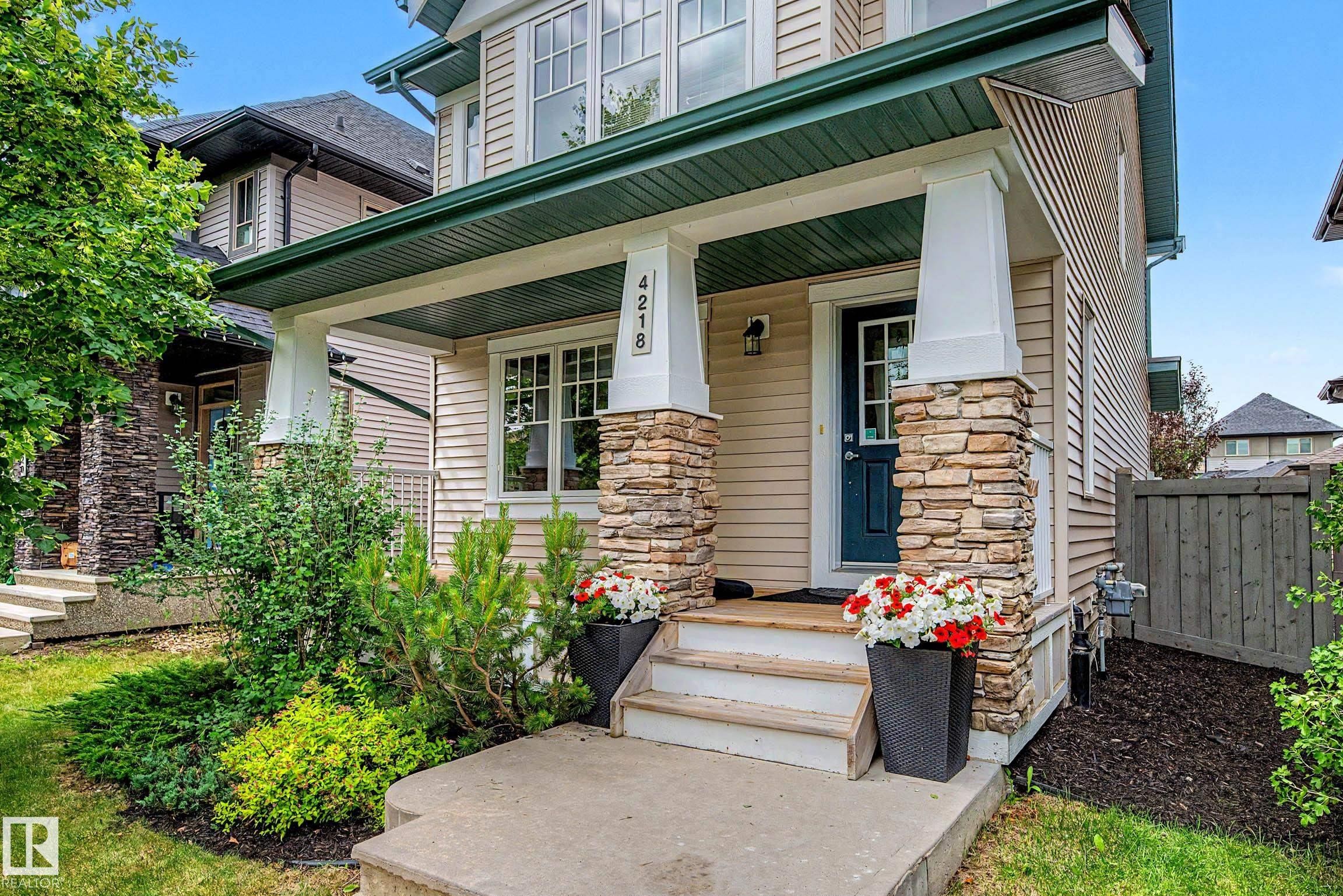 Inviting covered front porch with stone-wrapped columns and a dark blue entry door - 4218 Allan Link Link Sw, Edmonton, AB - Outdoor