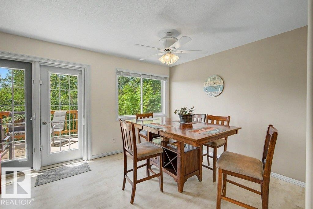 Dining area featuring wood-finish flooring, a ceiling fan with integrated lighting, and multiple windows - #39 2419 133 Av Nw, Edmonton, AB - Indoor Photo Showing Dining Room