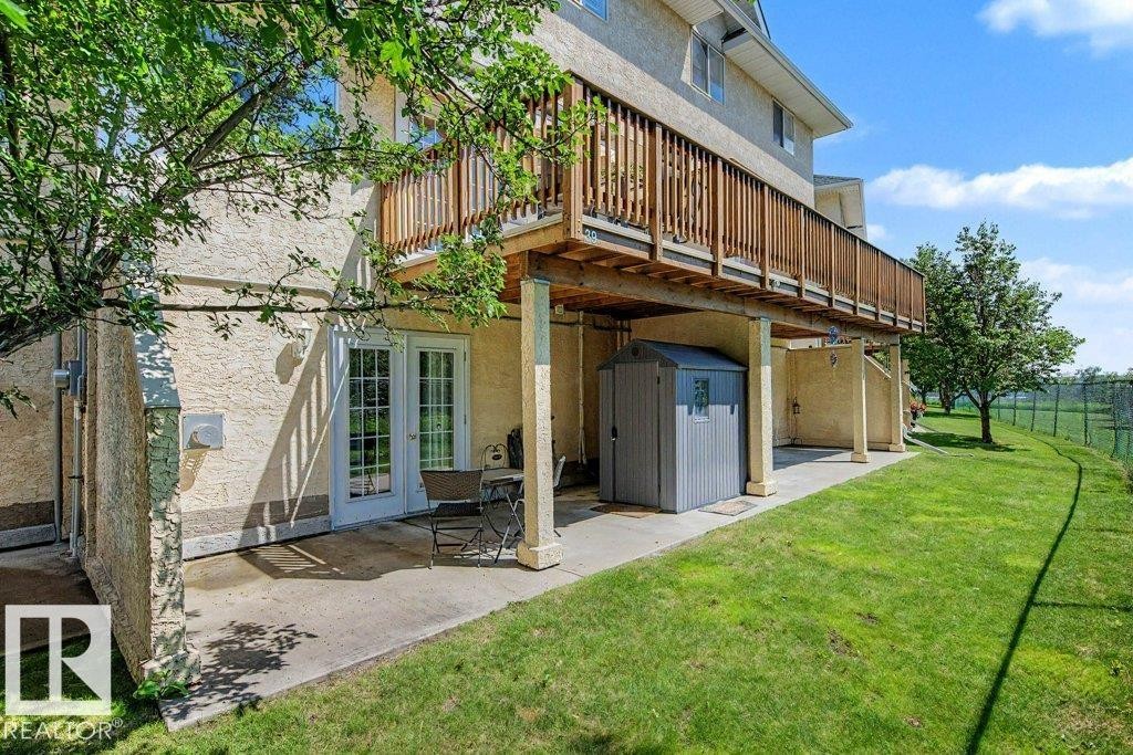 Lower-level patio with double French doors and an overhead wooden deck - #39 2419 133 Av Nw, Edmonton, AB - Outdoor With Deck Patio Veranda