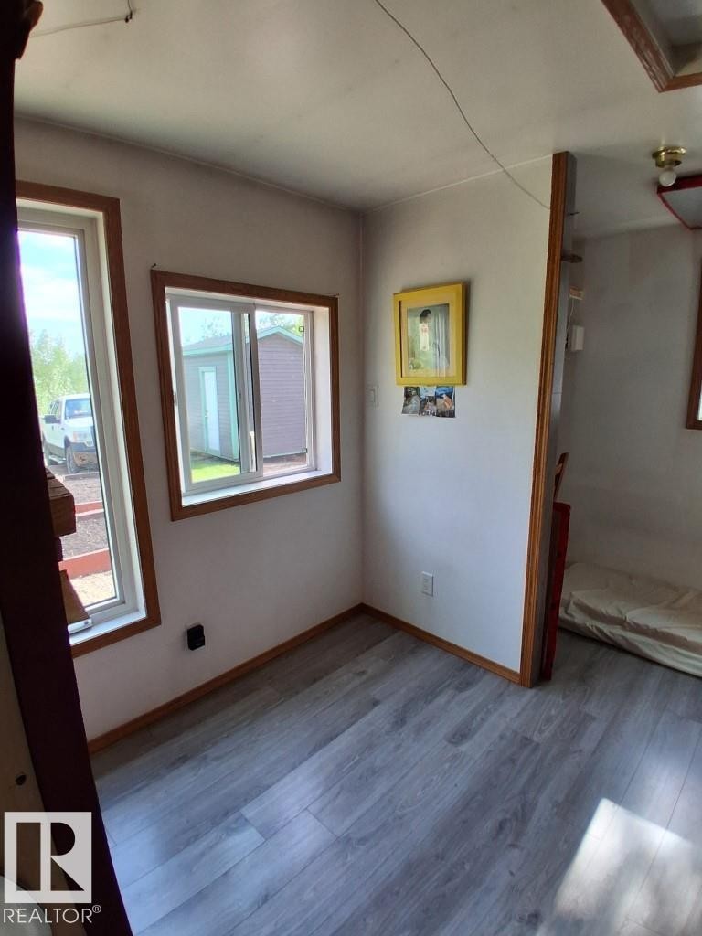 Interior space featuring wood-finish flooring, two windows with wood trim, and white walls - 204 Sandy Beach Way, Rural Two Hills County, AB - Indoor Photo Showing Other Room