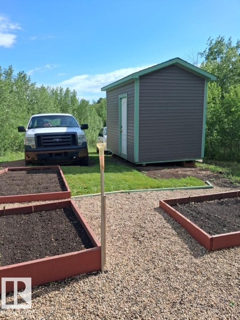 Outdoor storage shed featuring horizontal siding and a white entry door - 204 Sandy Beach Way, Rural Two Hills County, AB - Outdoor With Exterior