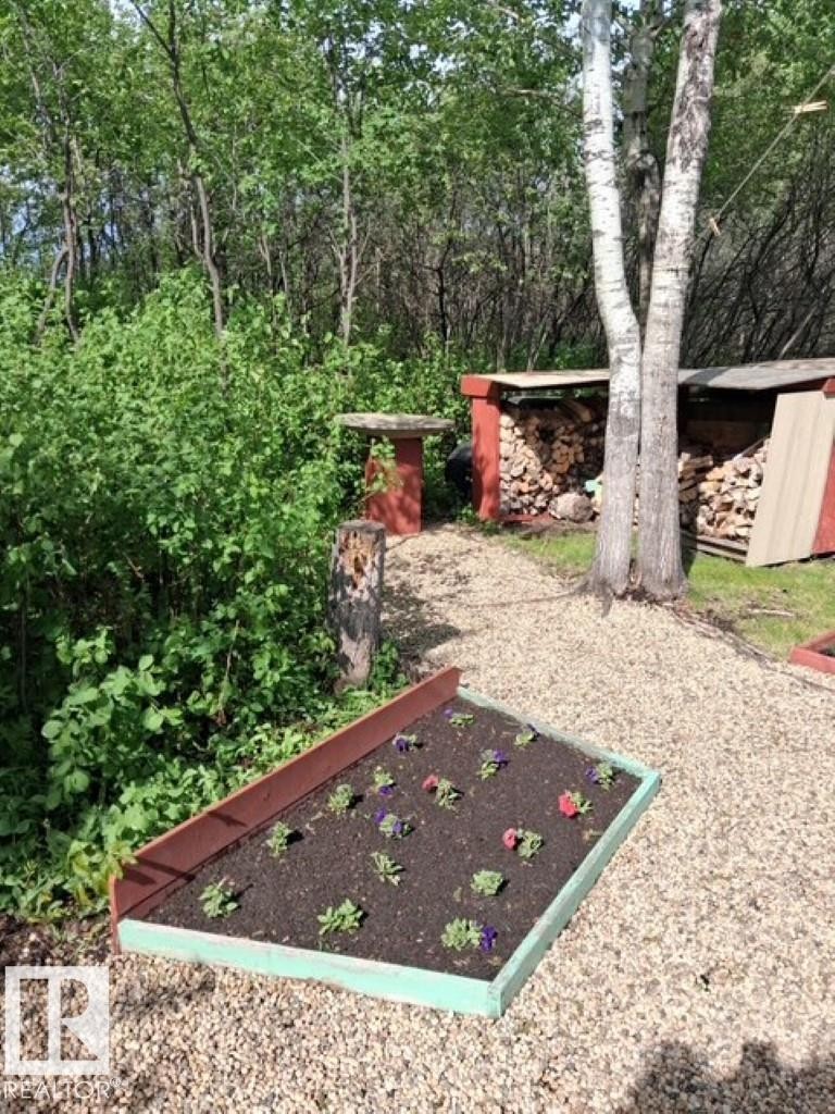 Raised garden bed with colorful plantings, set on a gravel path - 204 Sandy Beach Way, Rural Two Hills County, AB - Outdoor