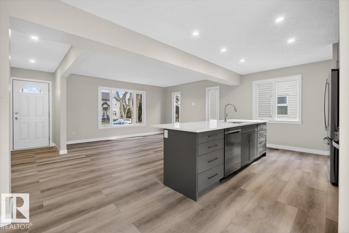 Open-concept interior featuring light gray walls, wood-finish flooring, and recessed lighting - 9723 65 Avenue Nw, Edmonton, AB