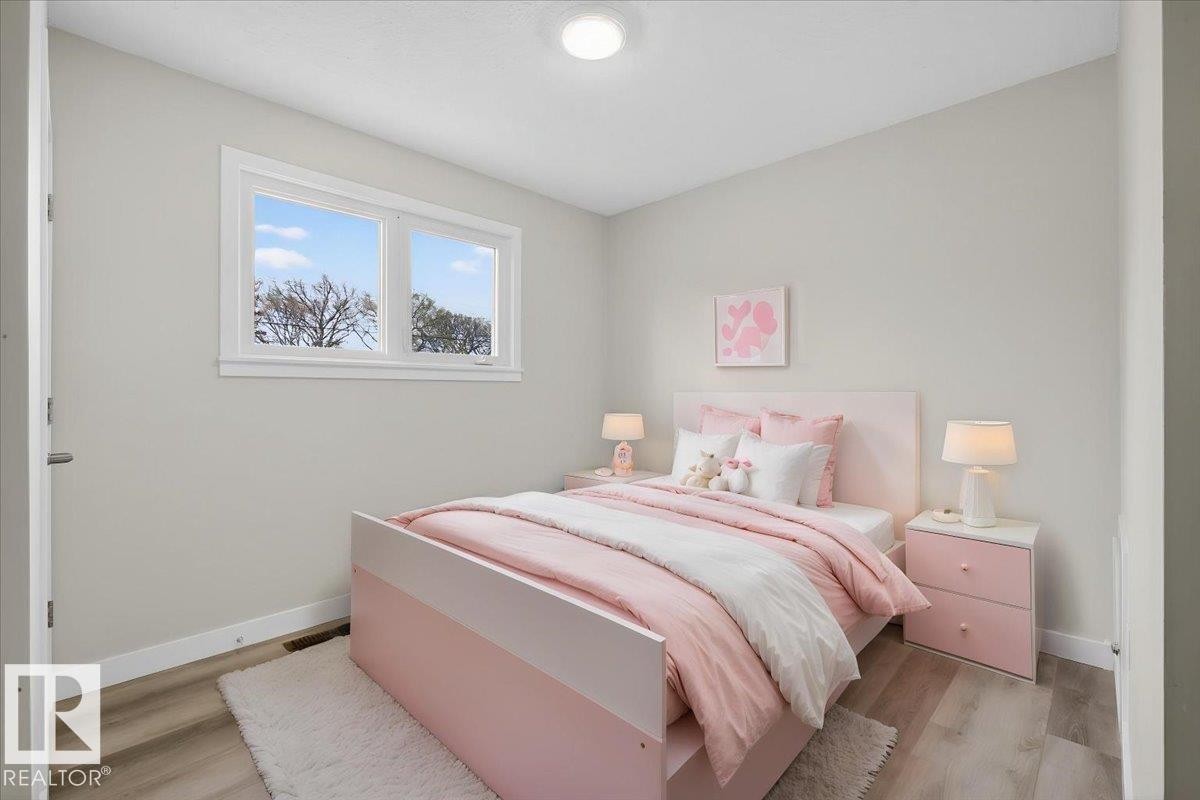 Bright room featuring wood-finish flooring, light grey painted walls, a flush-mount ceiling light, and a double window with white trim - 9723 65 Avenue Nw, Edmonton, AB
