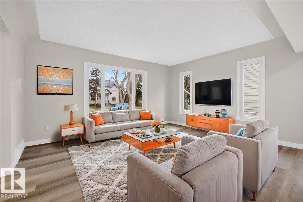 Spacious living area featuring a tray ceiling, wood-finish flooring, and light-toned walls - 9723 65 Avenue Nw, Edmonton, AB